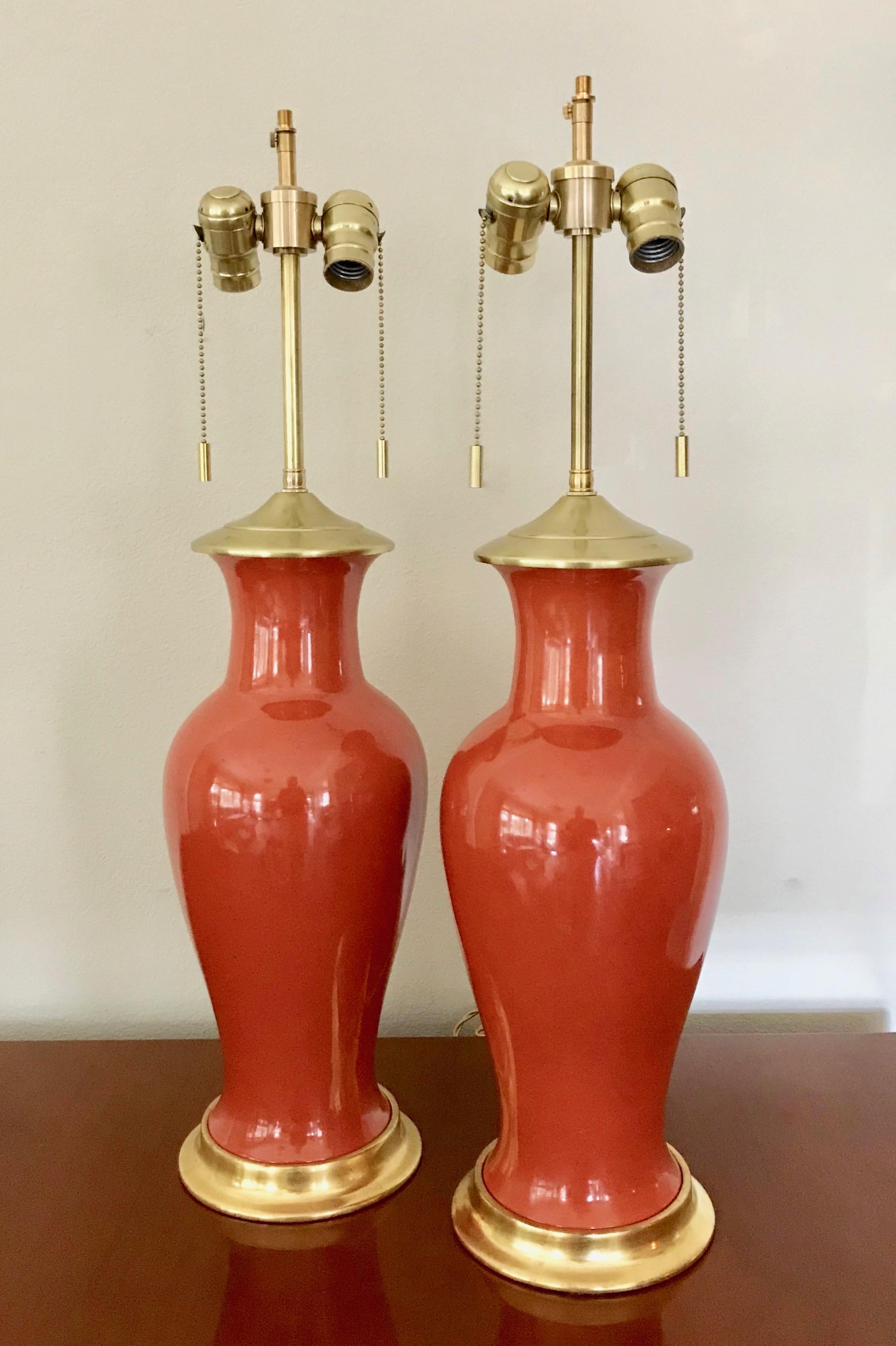 Vintage pair Japanese porcelain vases in striking orange glaze mounted as lamps with custom 23K water gilt turned wood bases with traditional red bole undercoat. Vintage lamps with in the style later made iconic by Christopher Spitzmiller. Lamp
