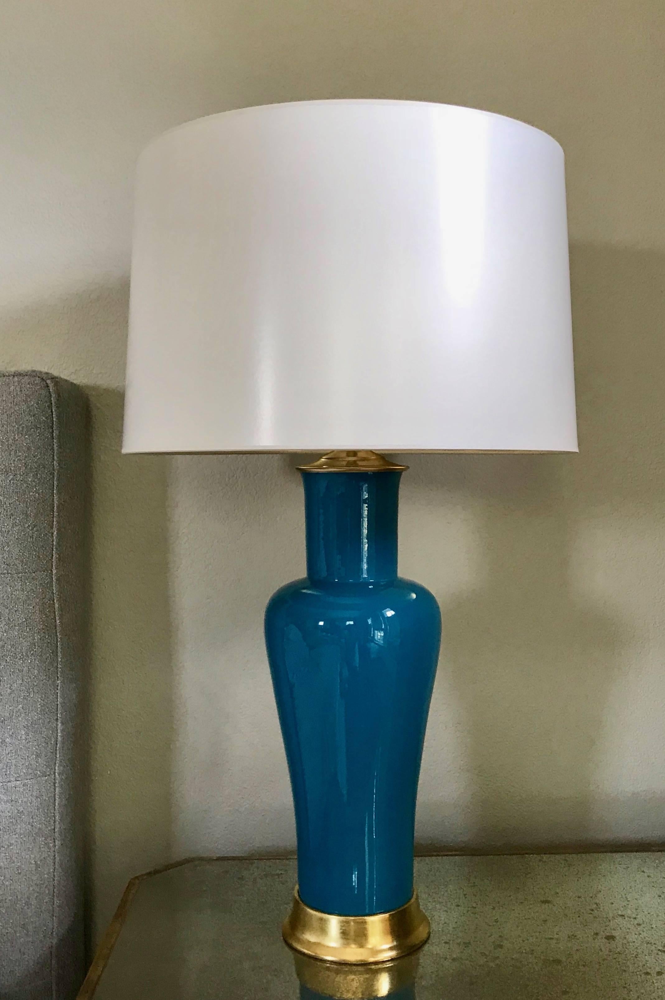 Pair of hand thrown porcelain lamps in a vibrant cobalt blue reflective glaze with custom 23-karat water gilt turned wood bases. Wired for US with on/off pull chain sockets, brass fittings and French style rayon covered twisted cord. Weighted bases