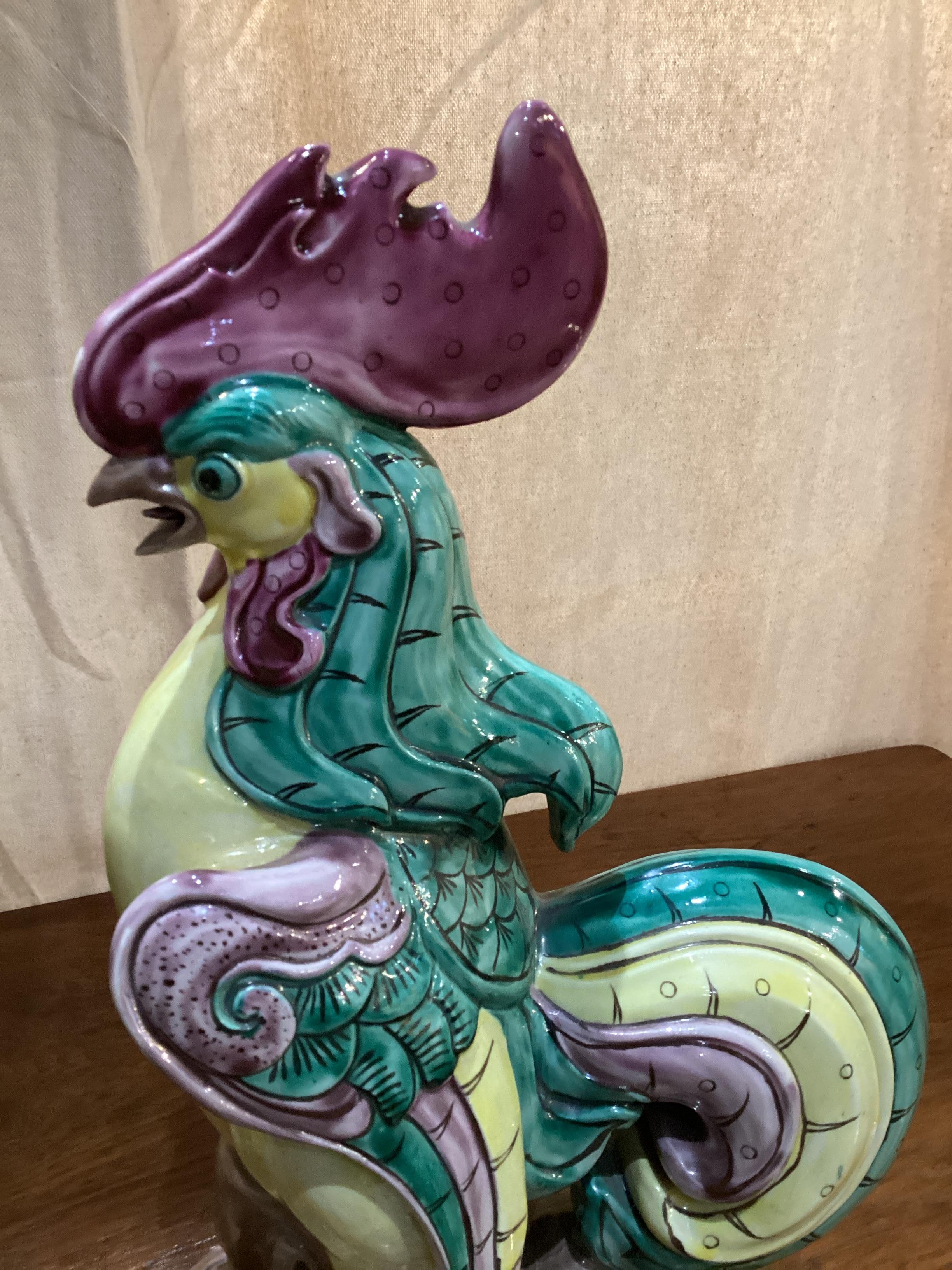 Paire de coqs en céramique chinoise aux couleurs vives. Des coqs chanteurs perchés sur un tronc, dans un plumage très coloré de jaune, de vert et de violet.