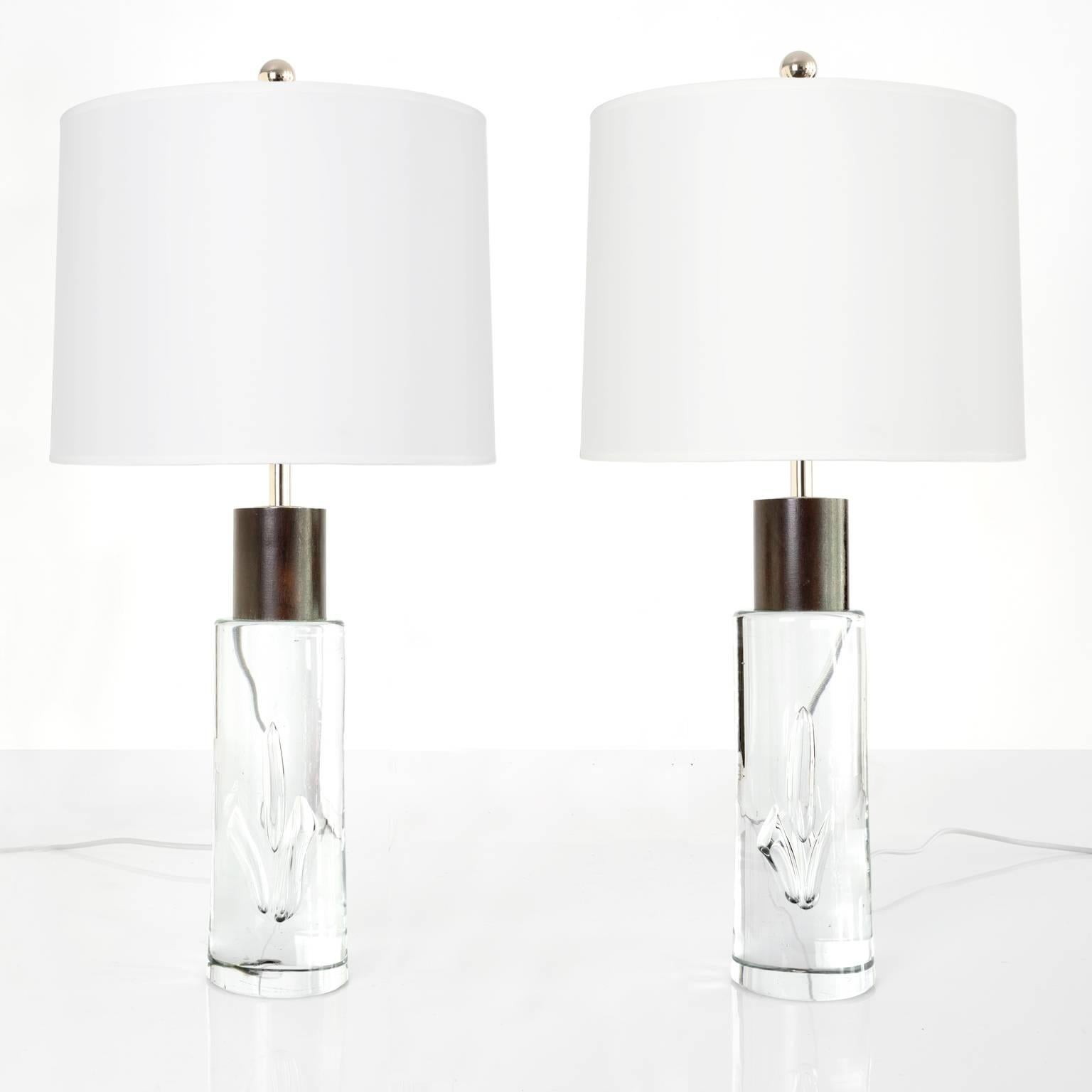 Pair of Vicke Lindstrand designed solid glass table lamps with mahogany details. The cylindrical forms have large air bubbles added to great effect and are topped off with carved pieces of mahogany. Newly rewired for the USA with nickel plated stems