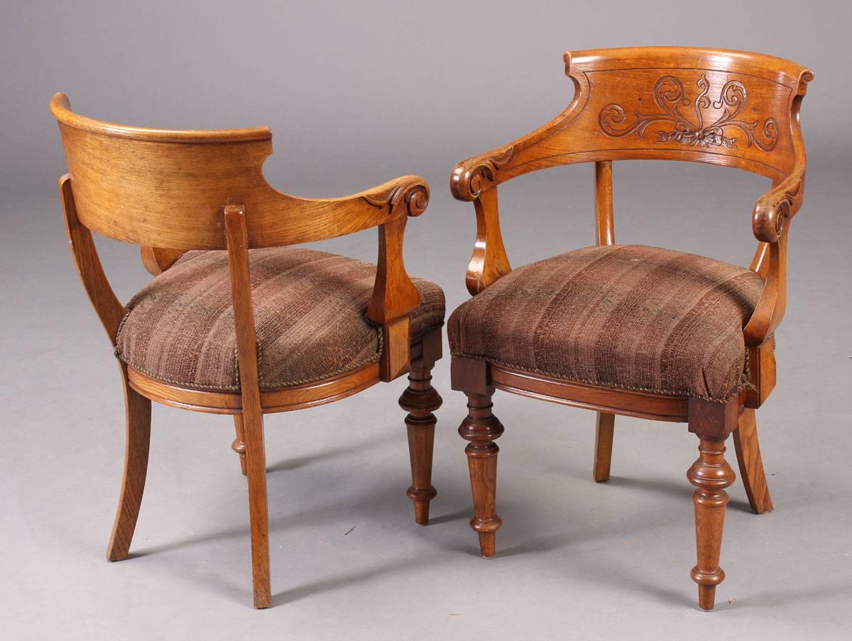 Handsome pair of Victorian period armchairs in oak with carved foliate scroll on the back. Turned front legs and sabre back legs. Good desk chairs. More available.
 