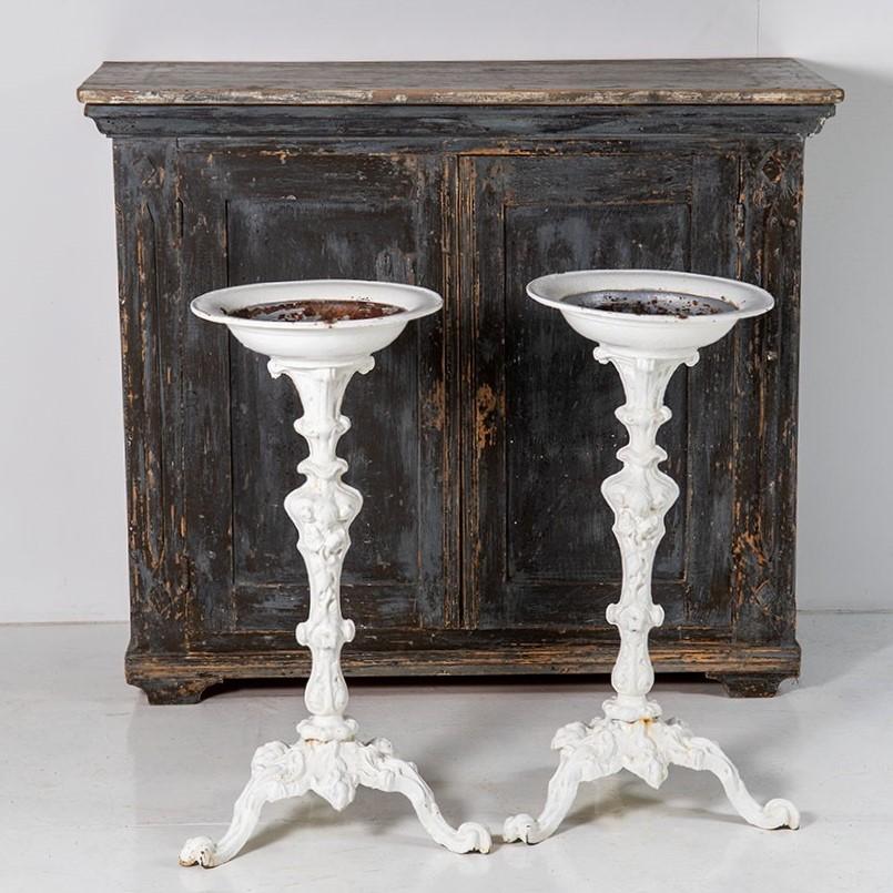 A decorative pair of Victorian torchère stands in cast iron. Good form with layers of old paint, these would have been used in an internal room setting rather than garden hence their condition. Nicely detailed columns with Corinthian tops leading to