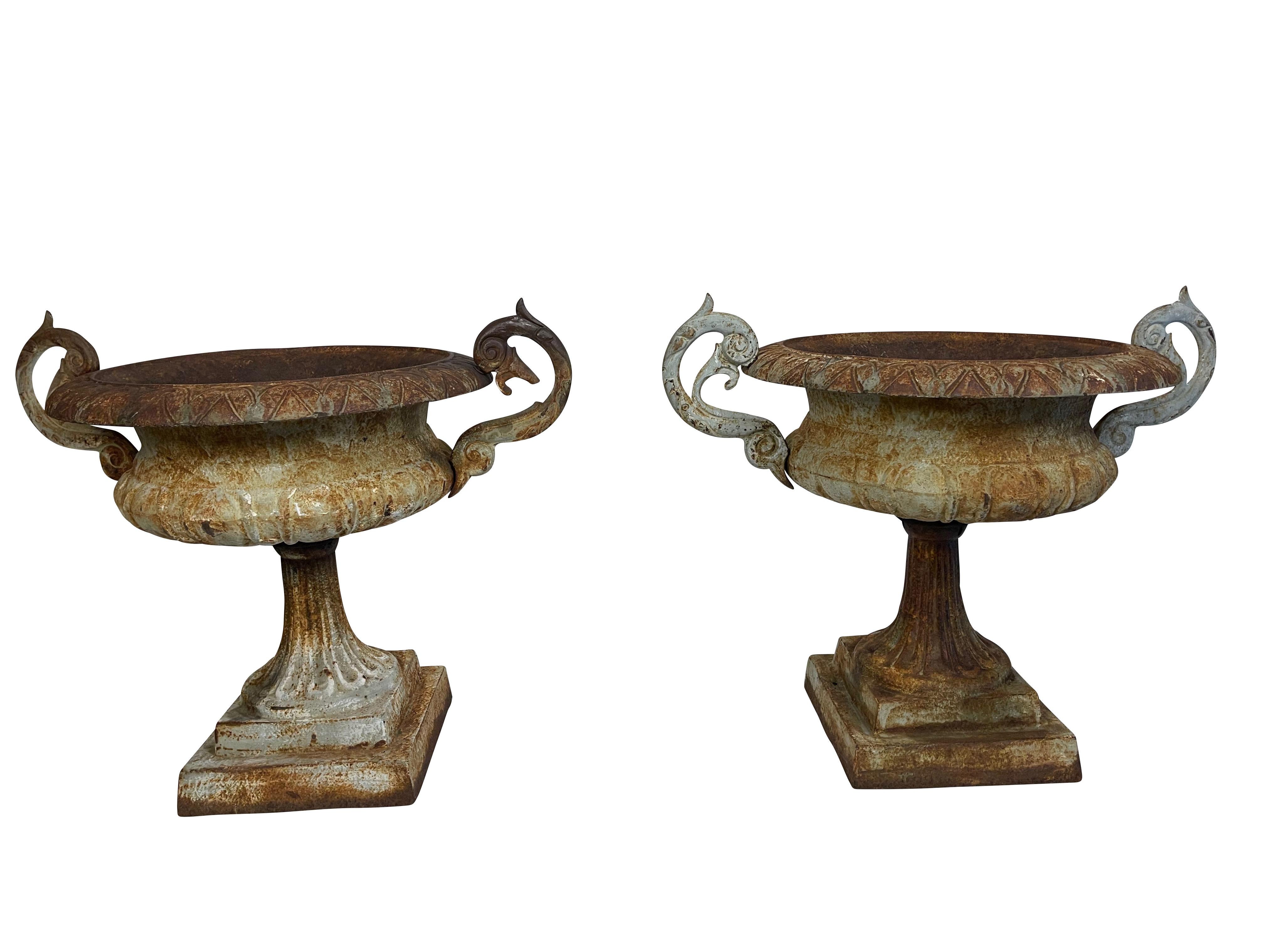 Pair of round Victorian cast iron jardinières/ planters with long reticulated pedestal, decoratively scroll form handles and egg and dart form decoration along the flared rim with a hole in the bottom for drainage. The basin sits on a square base.