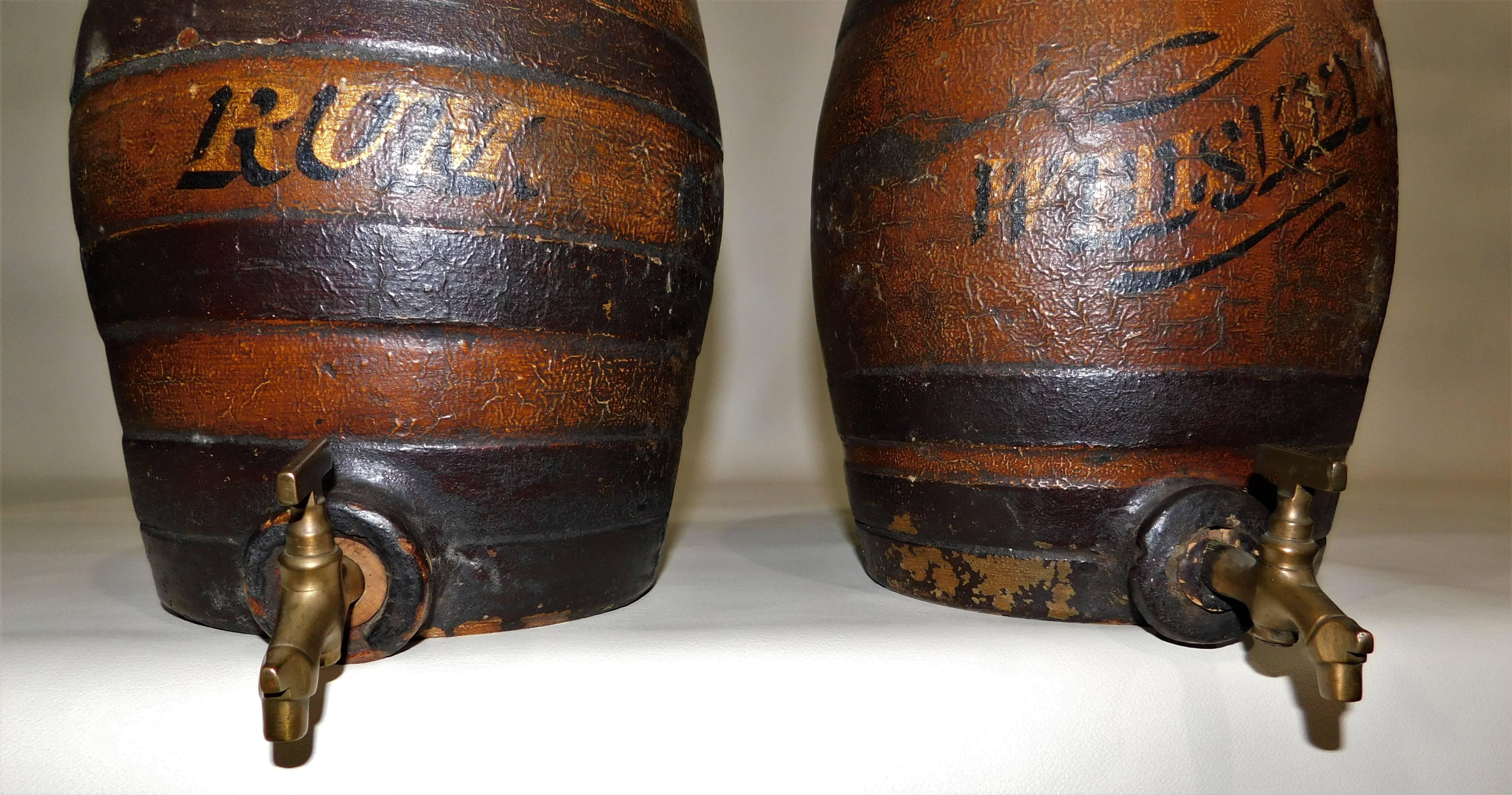 Large 19th century antique stoneware pottery keg barrel cask whiskey and rum bar liquor dispensers with brass spigots. Brass spouts are 2 inches long, rum keg is 10 inches high, whiskey keg is 10.5 inches high.