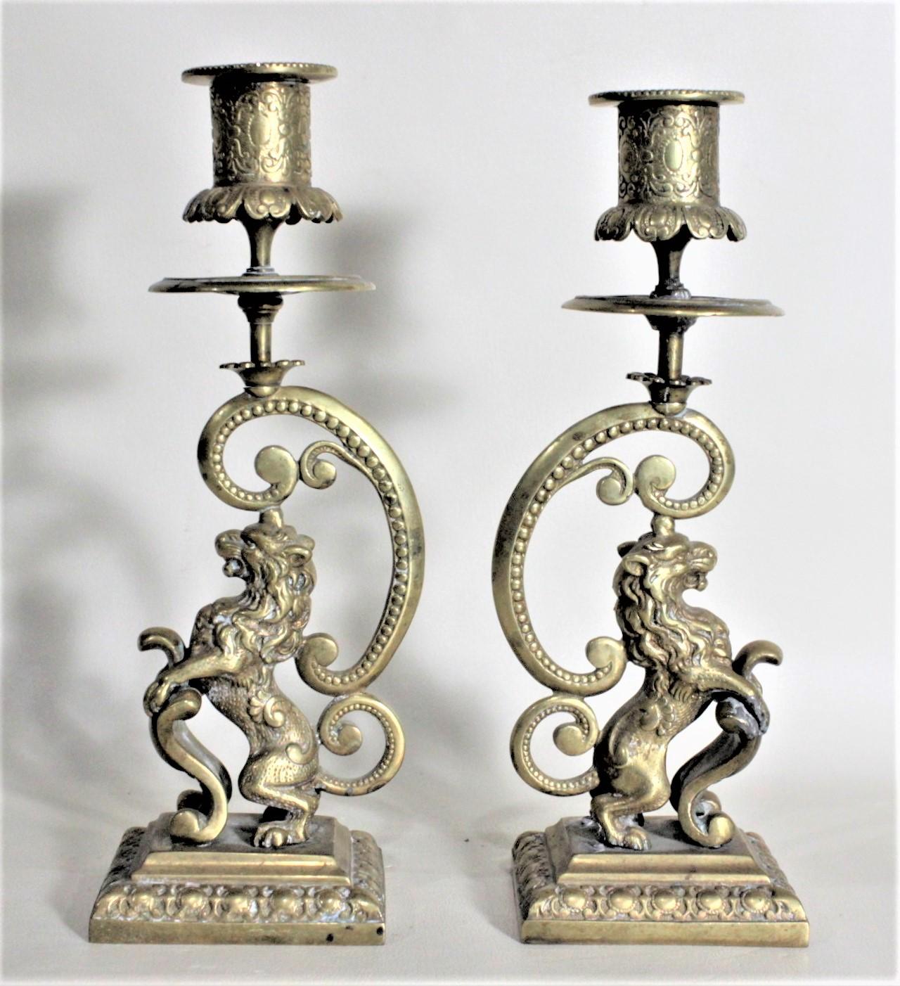 This pair of solid brass candlesticks are unsigned, but believed to have been made in England in circa 1880, in the period Victorian style. The candlesticks are quite detailed in their casting and depict a rearing male lion with one outstretched paw