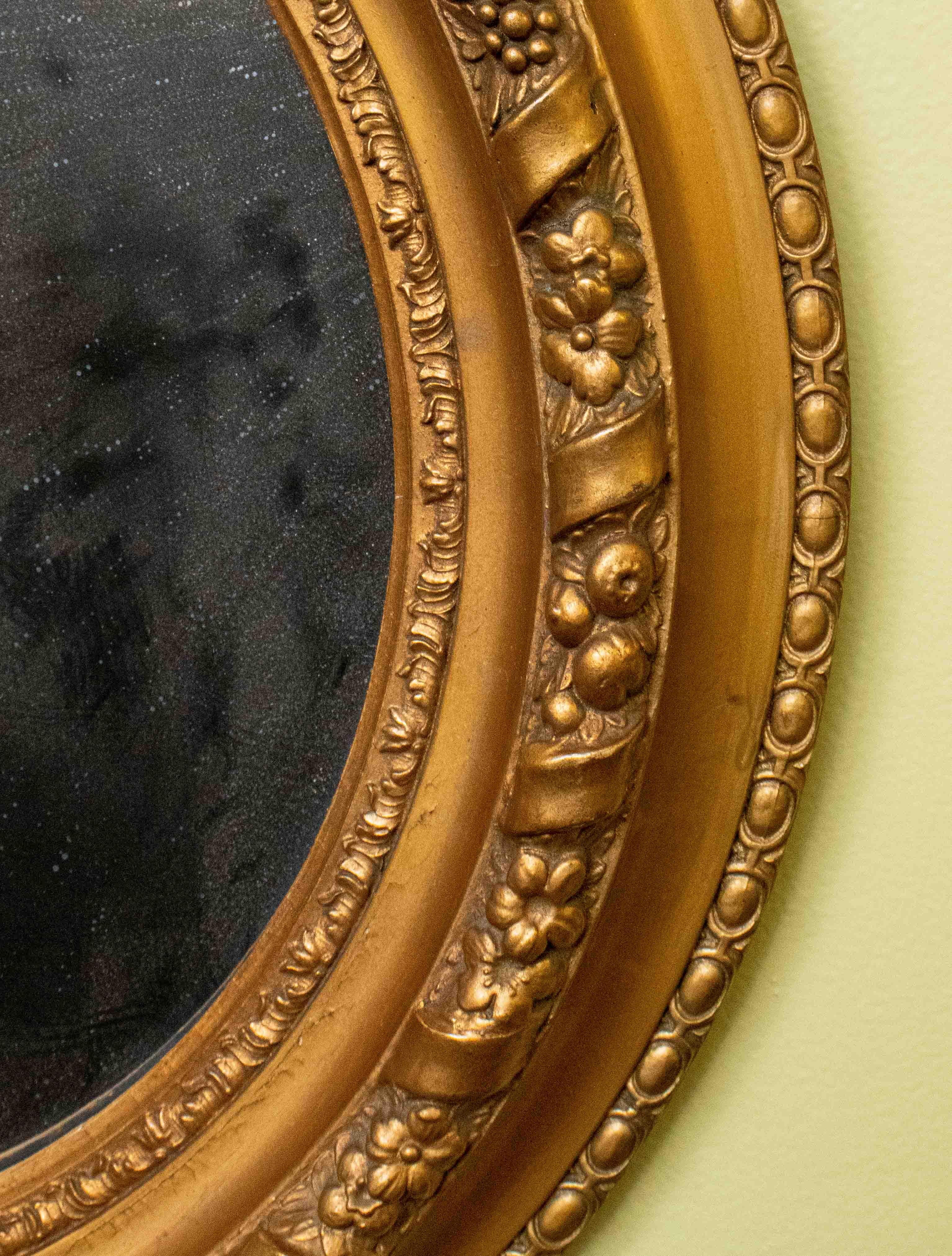 A pair of antique Victorian gilded oval mirrors.