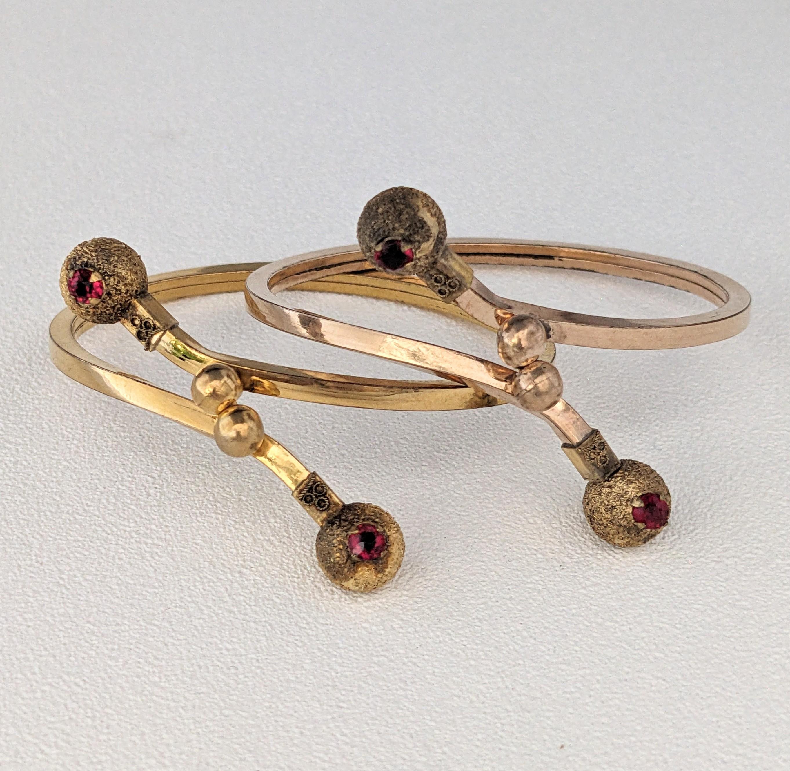 Coppia di bracciali vittoriani in oro della fine del XIX secolo. Disegnato come un motivo a incrocio con elsi a sfera testurizzati, ciascuno dei quali è incastonato con una pasta di rubino. Ciascuna si apre con una chiusura autobloccante. Dimensioni