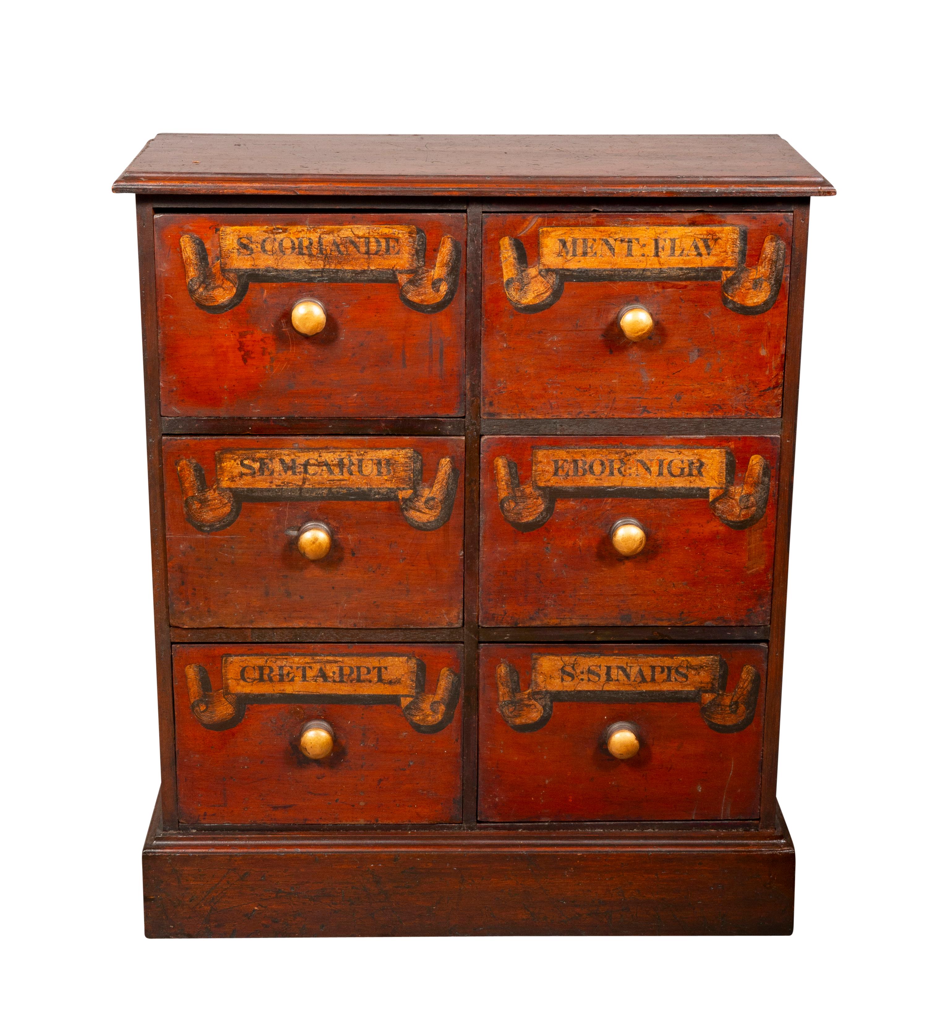 Each with a rectangular top over six drawers with a red wash and gilt lettering. Wood knobs. Plinth base.