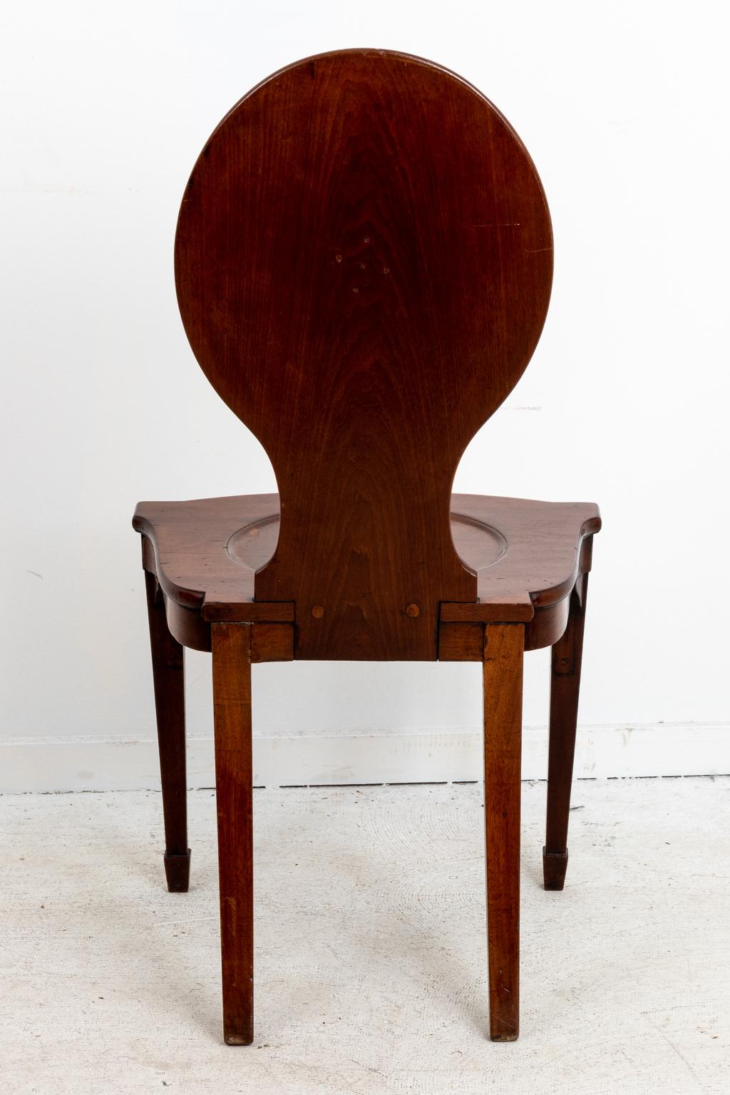 Pair of Victorian mahogany hall chairs with oval seat back, plain tapered legs, and spade turned feet. Please note of wear consistent with age including minor scratches and finish loss.