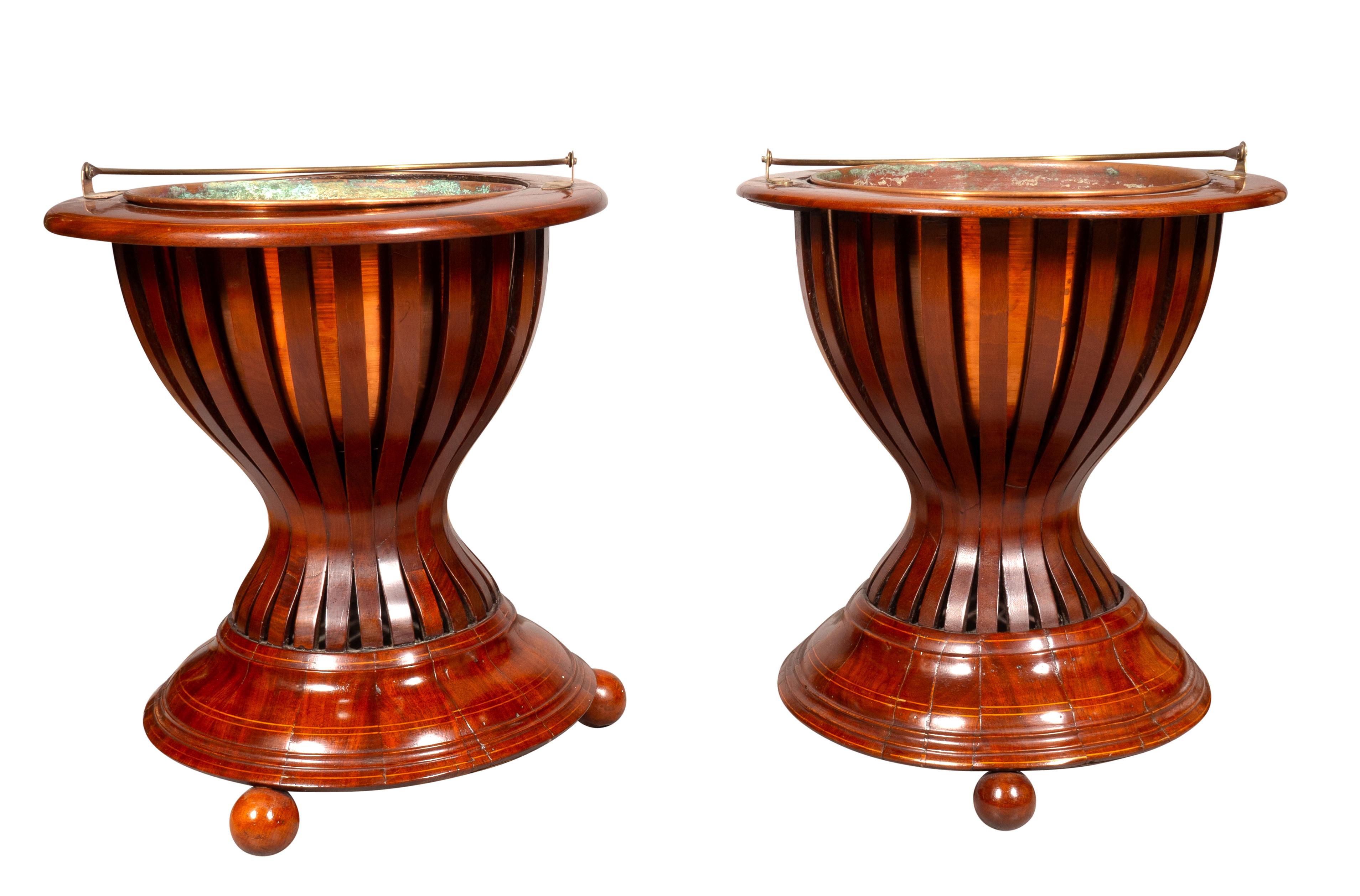 Each with brass liners and brass bail handles. Urn shaped with open slat work and circular base with ball feet.