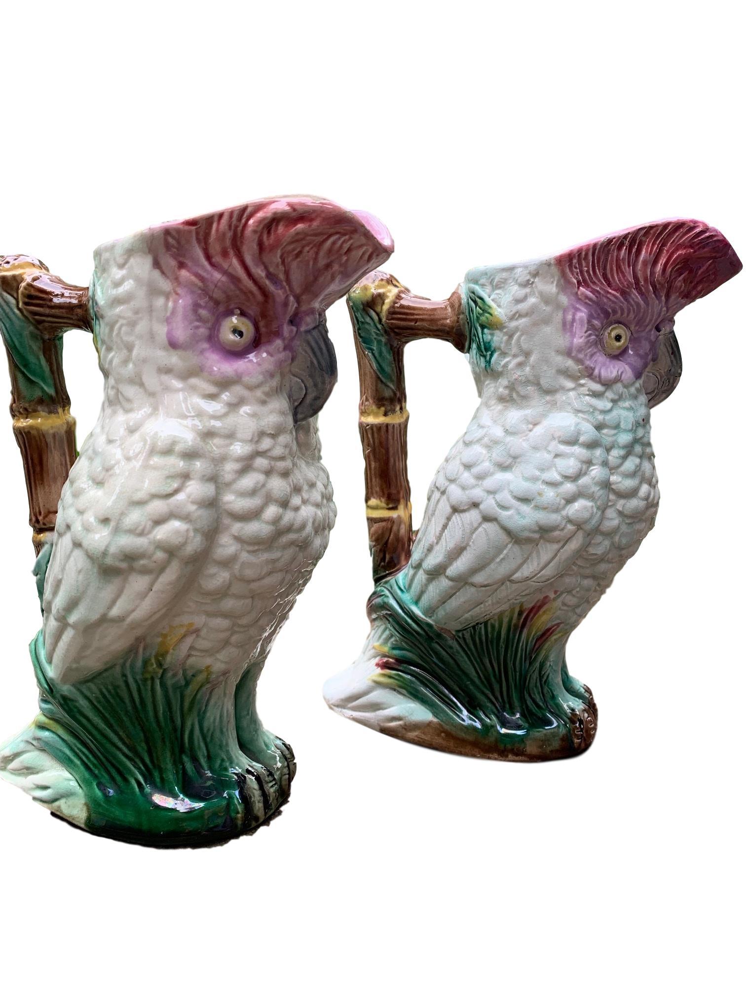 Beautiful pair of Majolica Cockatoo pitchers in good condition. Bright coloration with bamboo handle, circa 1800s. Slight wear consistent with age and use.