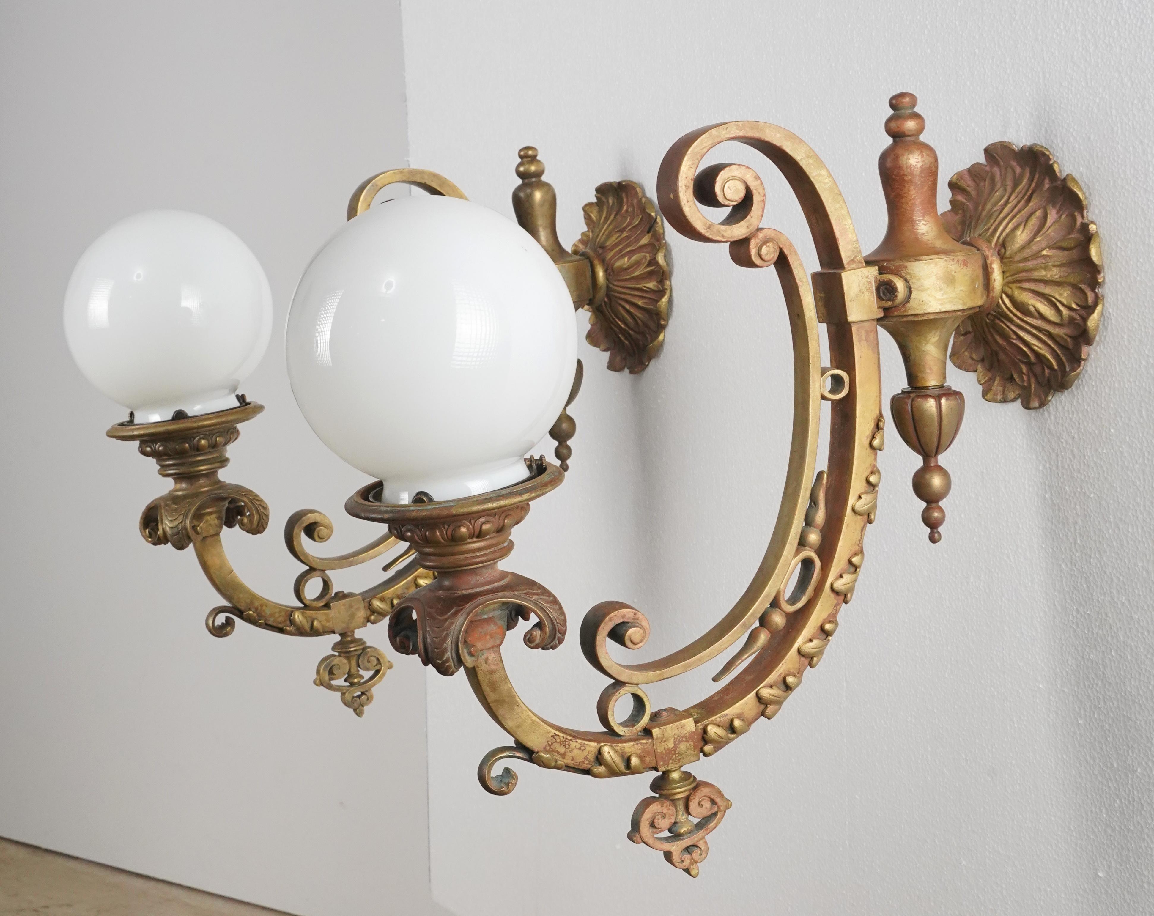 Victorian style heavy bronze wall sconces featuring ornate scrollwork paired with ball shaped milk glass globes. Each sconce requires one Edison style light bulb. Cleaned and restored. Good condition with surface wear from prior use. Priced as a