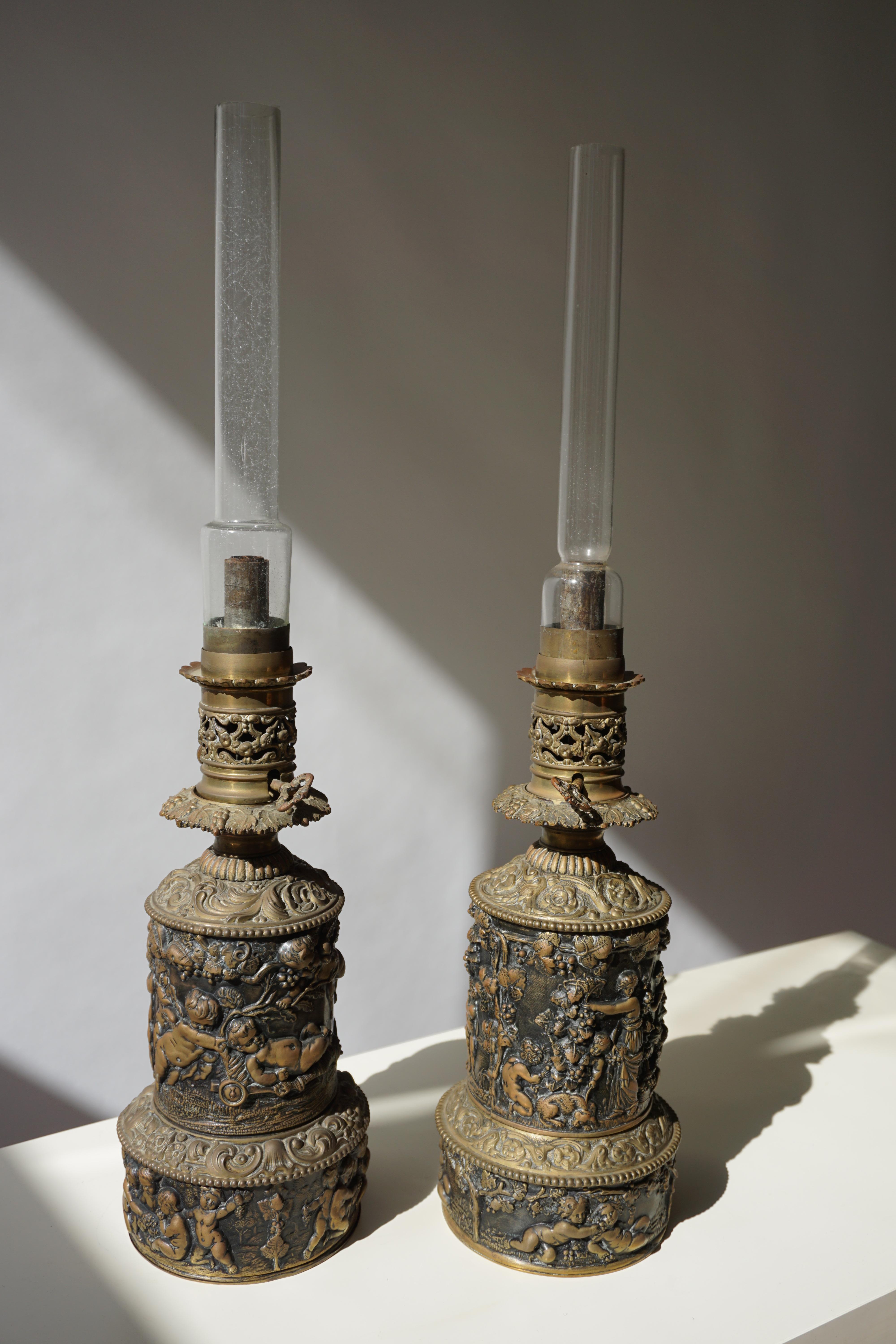 A pair of impressive / monumental Victorian copper sculptural oil table lamps showing putti figures / wingless cherubs with grape leaves and swirling vines. Paired with glass shade.They are not in a working condition.

Dimensions
Height base 35