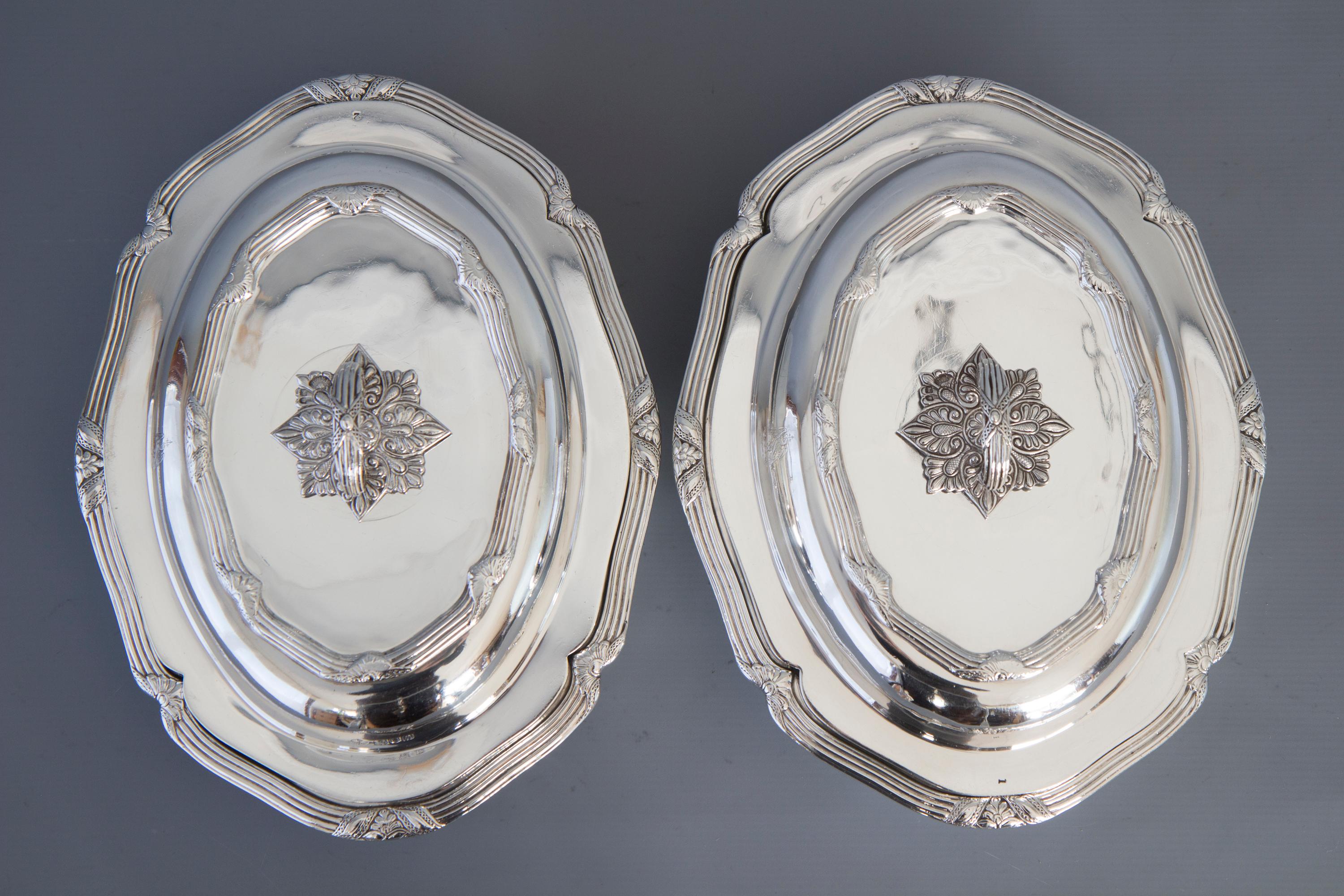 A high quality pair of silver Victorian entree dishes of shaped over form. Each rim decorated with reeded borders interspersed with floral palmettes. The lid with conforming decoration. The handles of star form floral pattern and conforming loop