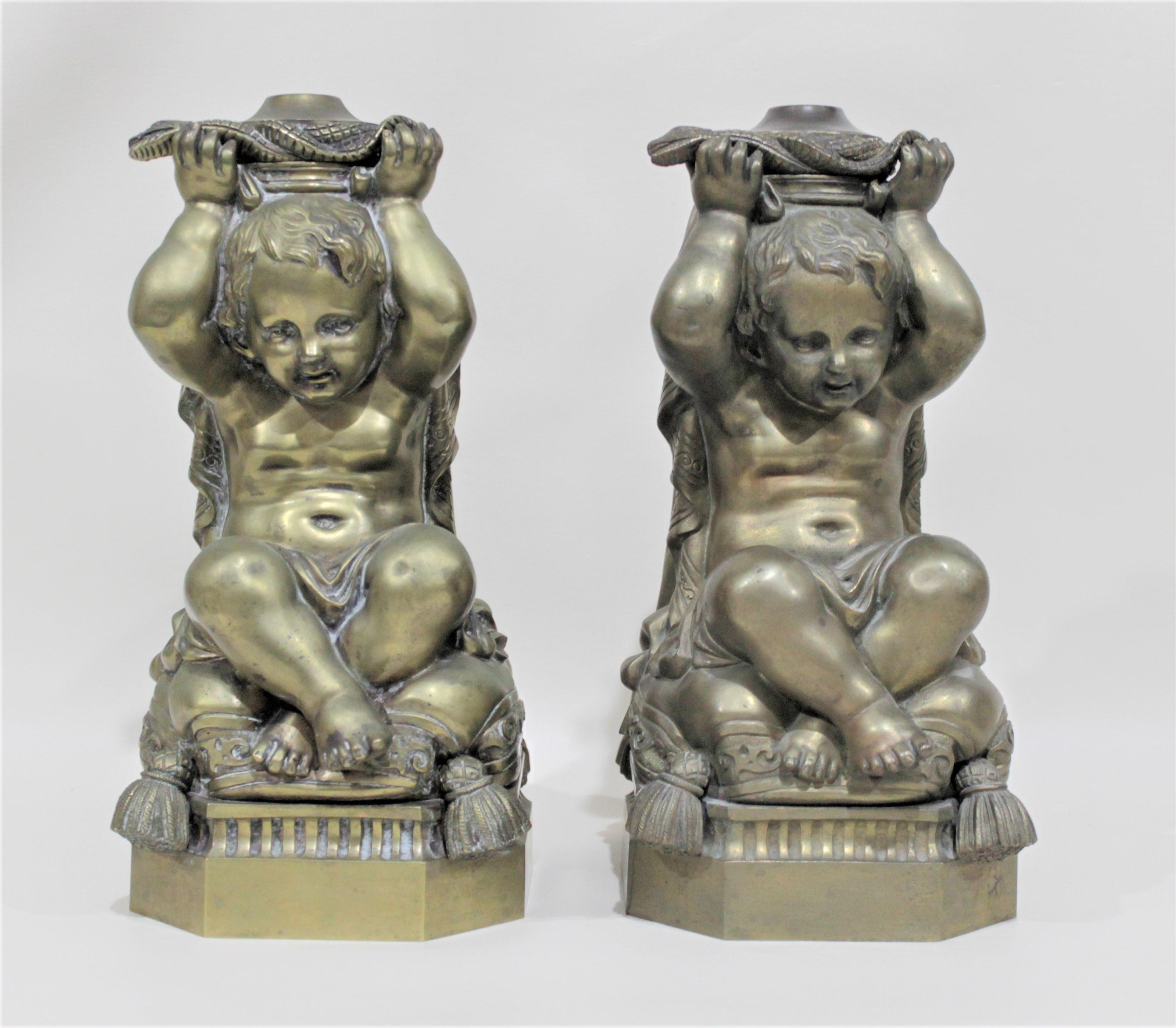 This matched pair of solid cast bronze figural cherub oil lamp bases are unmarked, but presumed to be made in the United States during the Victorian period. The bases are very detailed in their casting on all four sides and feature figural snakes or