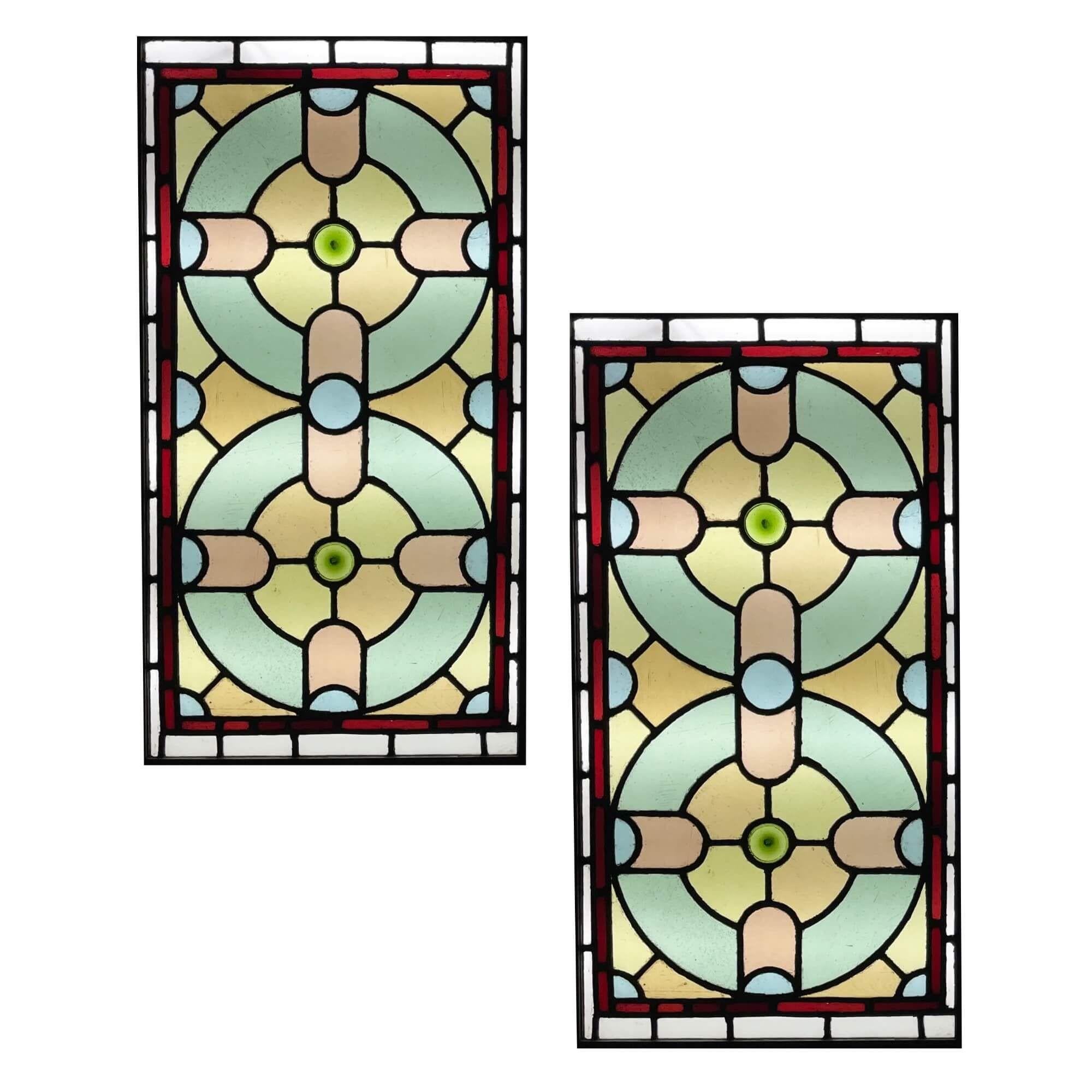 A pair of late Victorian stained glass window panels originating from England, circa 1900. These colourful stained glass windows are tall in scale and are currently fixed into wooden frames. The panels are decorated with shapes that morph into one