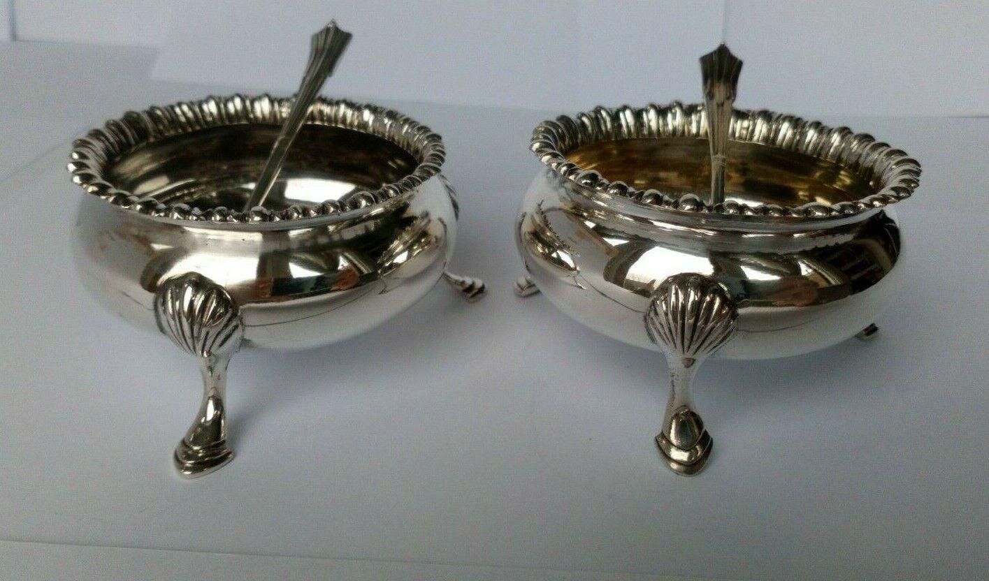 Pair of Victorian Sterling Silver Salt Dips & Spoons by Elkington & Co Ltd, 1898

In very good condition, this is a lovely set. They each stand three delicate hoof feet. They have striking borders and would look wonderful on any table.
The spoons