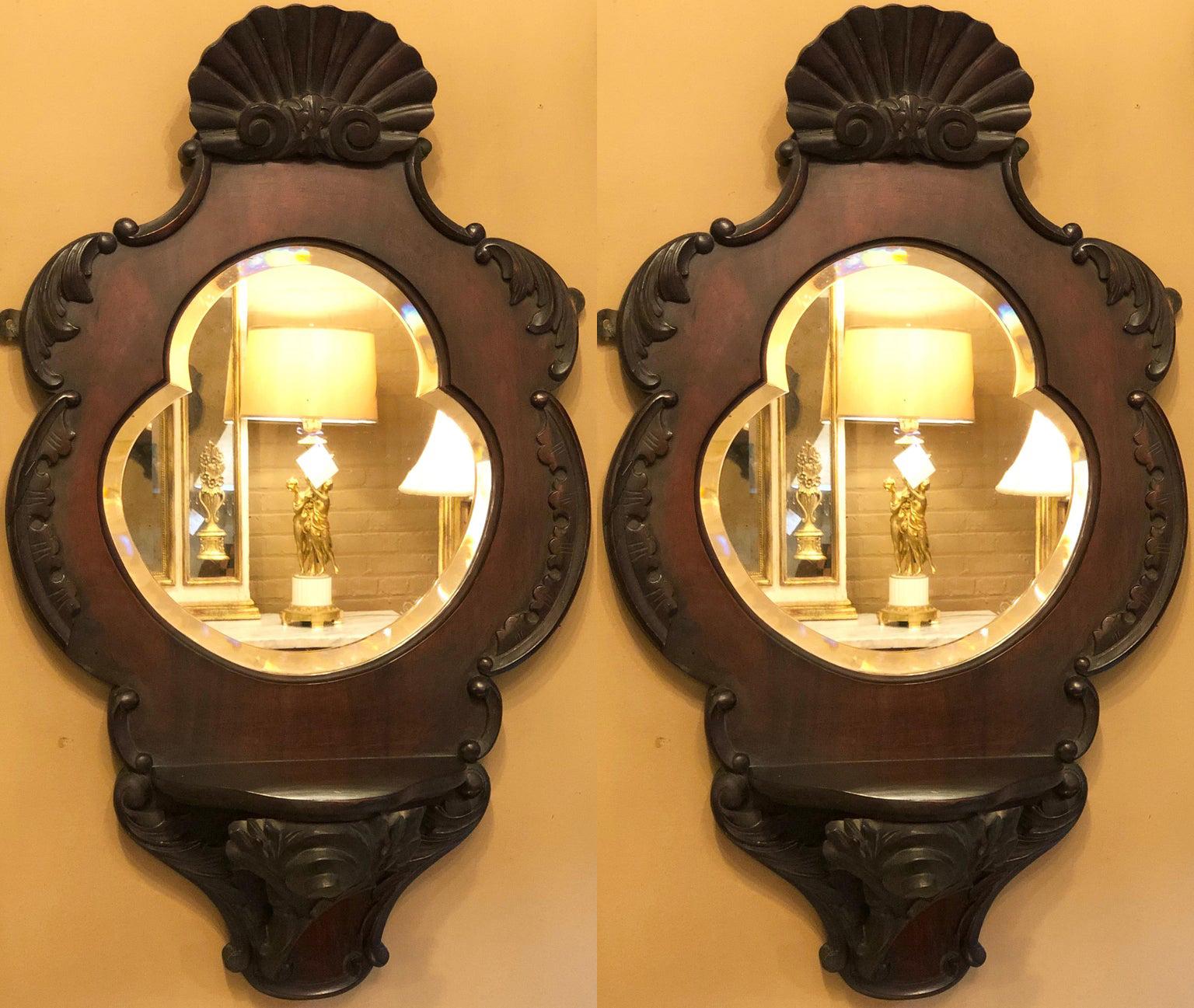 Pair of Victorian wall mirrors each in a heart shape. The beveled heart shape center mirror flanked in a mahogany Victorian carved frame. The pair having a small shelf.