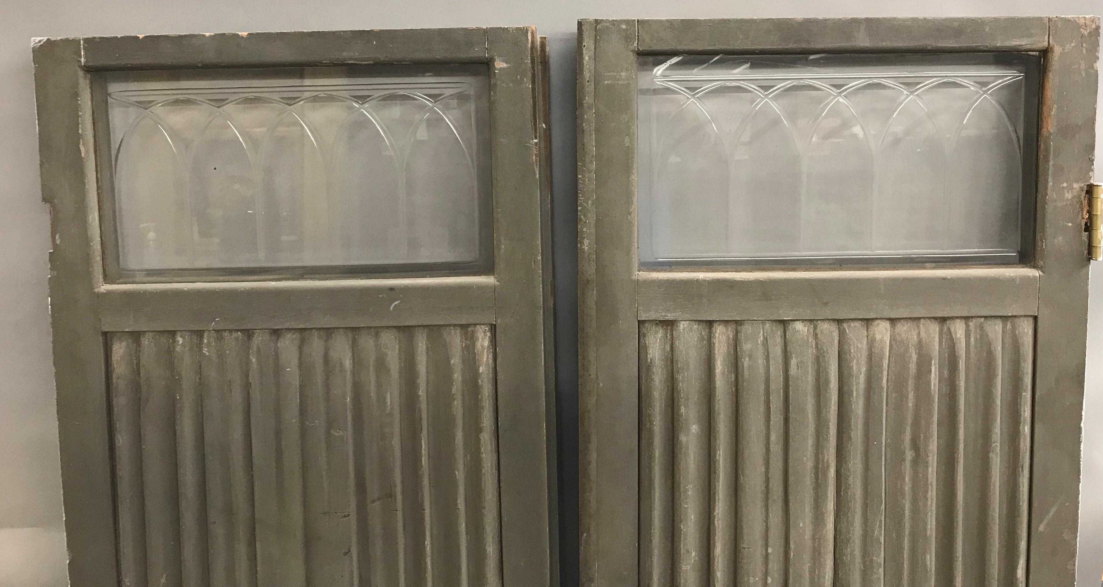 A fine pair of Victorian wooden doors from a horse-drawn hearse or funeral carriage with rectangle glass transoms at the top of each, featuring relief drapery carvings on each in old gray paint. The pair are probably English in origin, dating to the