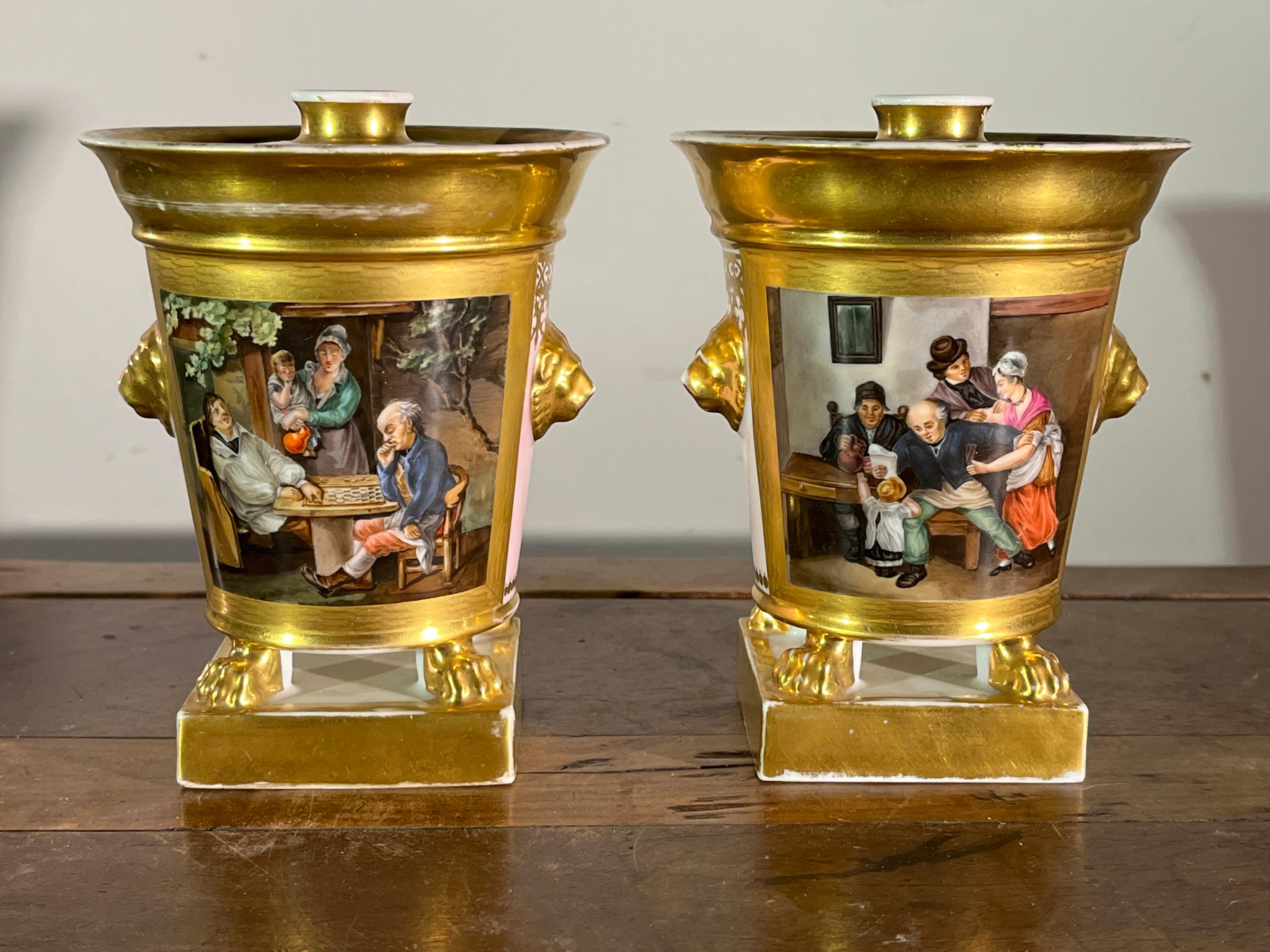 A pair of Old Paris porcelain potpourri urns circa 1790 with original lids, hand painted with genre scenes depicting 18th century life, lion mask handles, gilt decoration and a pink ground on the reverse. Museum de accession. 