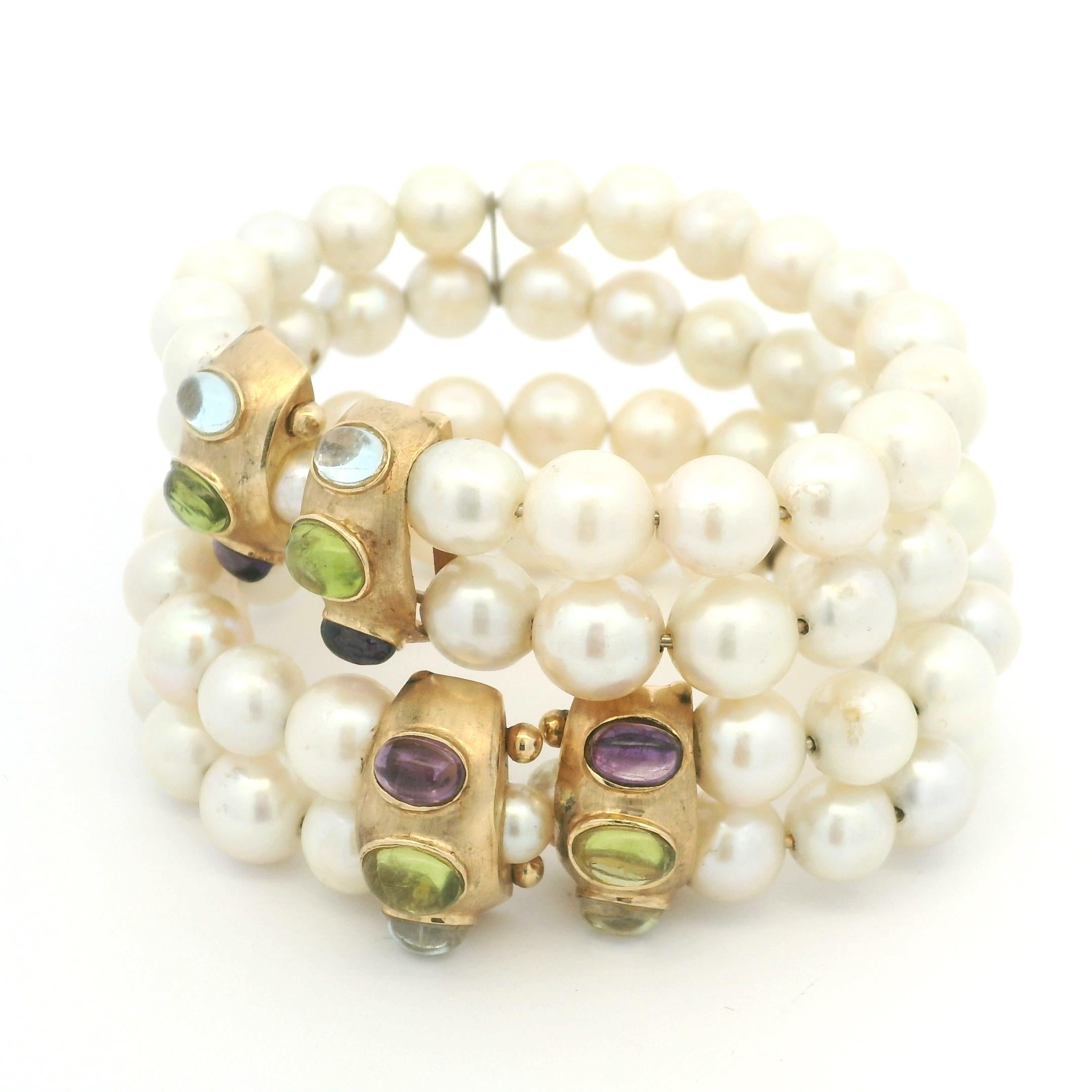 A rare matched pair of vintage bracelets, crafted in 14K yellow gold and together weighing 90.23 grams. Each bracelet is composed of luminous freshwater pearls arranged in double rows, accented by gold barrel stations set with colorful cabochon