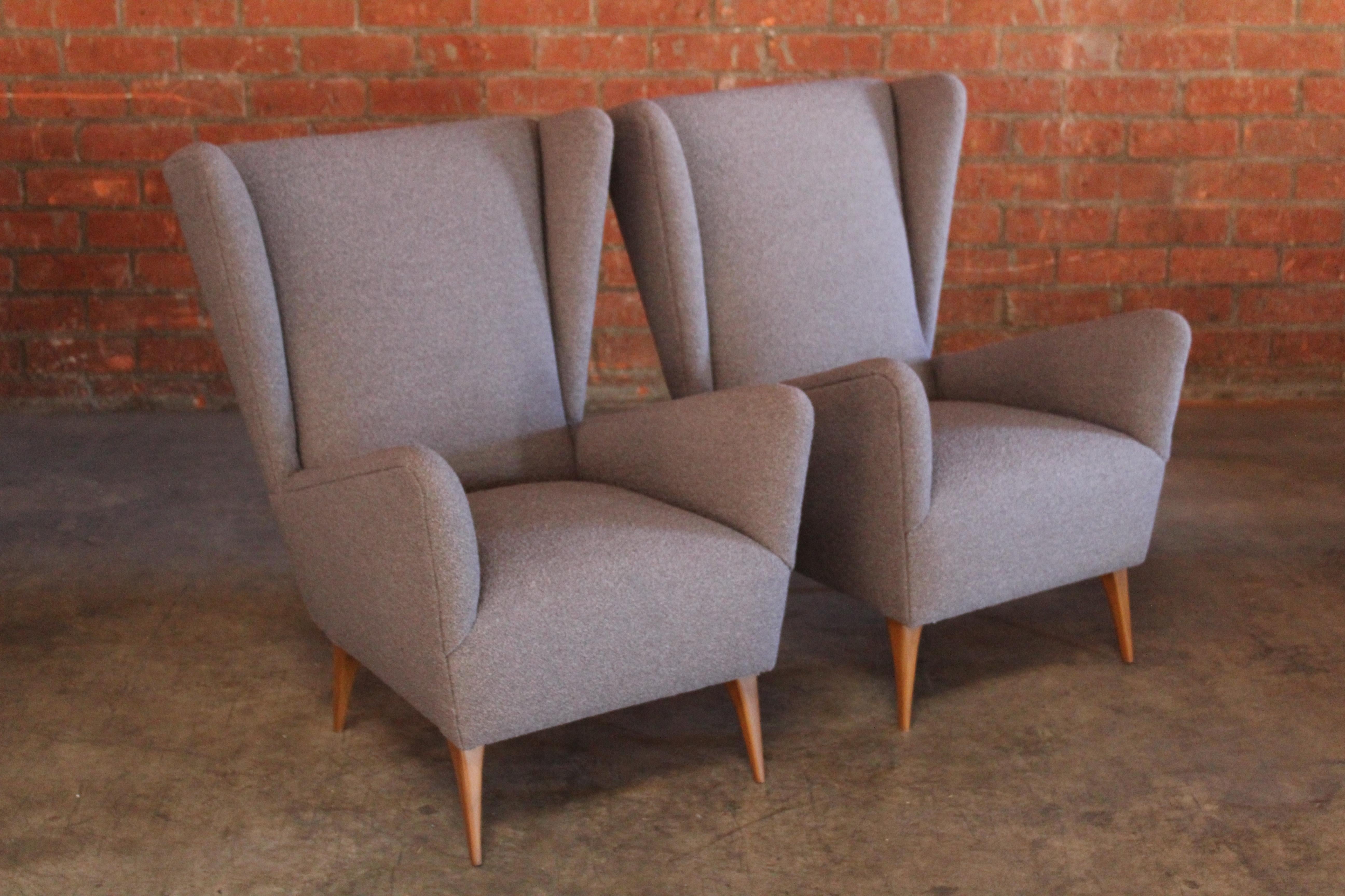 Pair of vintage 1950s highback Italian lounge chairs. The pair have been restored and reupholstered in a wool blend Italian made grey bouclé. The legs are solid walnut and have been refinished. In overall excellent condition. Sold together as a pair.