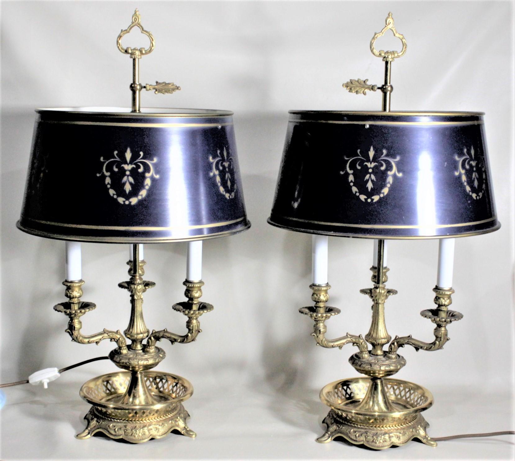 This pair of ornately cast brass Bouillotte lamps are unsigned, but presumed to have been made in France in approximately 1920 in the French Country style. The lamps have three chandelier arms which are nicely decorated with a leaves and flowers,
