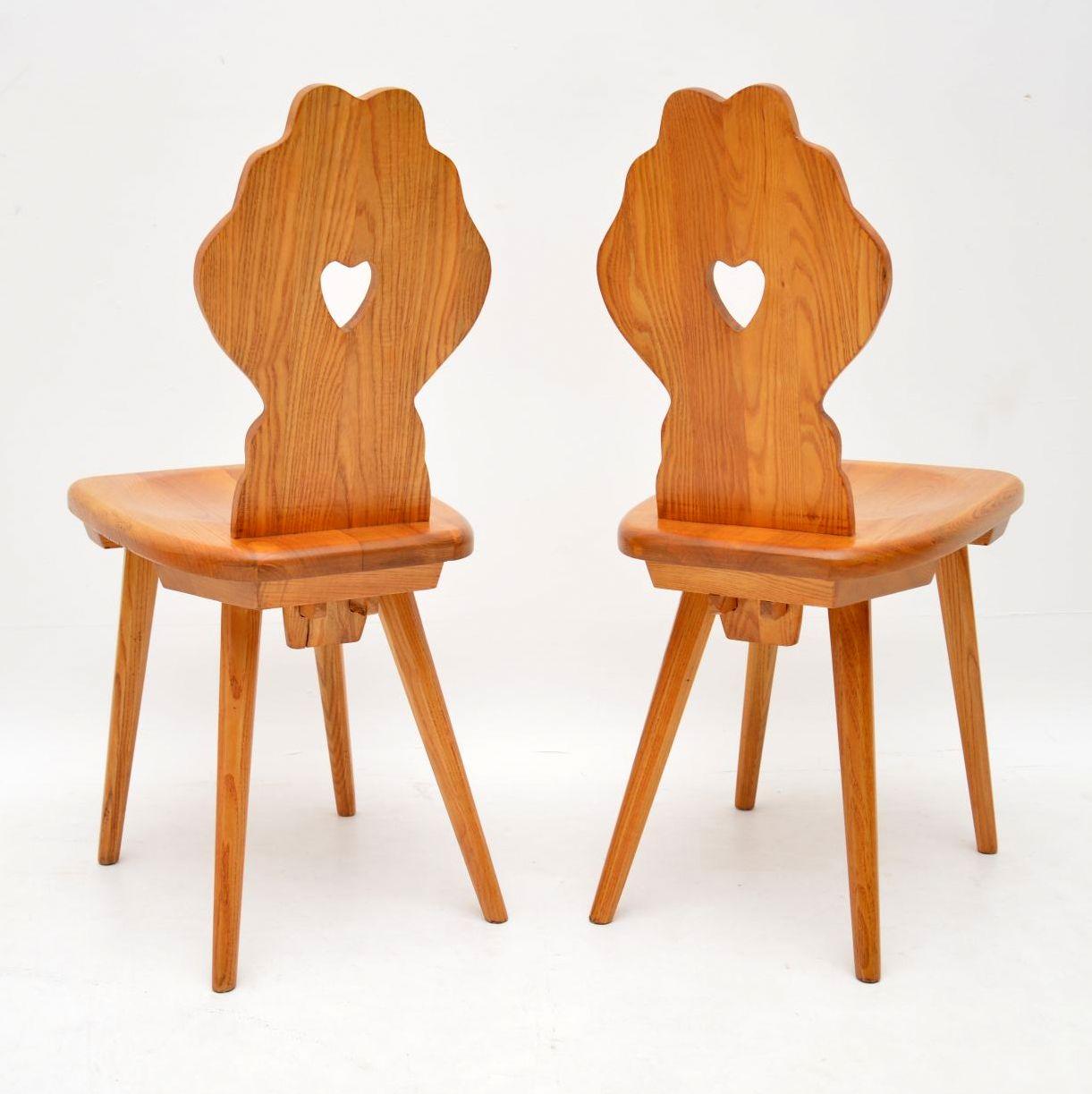 A stunning pair of vintage side chairs in solid Elm. These were made in Switzerland and date from circa 1950s. They are of amazing quality and have a beautiful design, with elegant splayed legs, shapely backs and cut out heart motifs. We have had