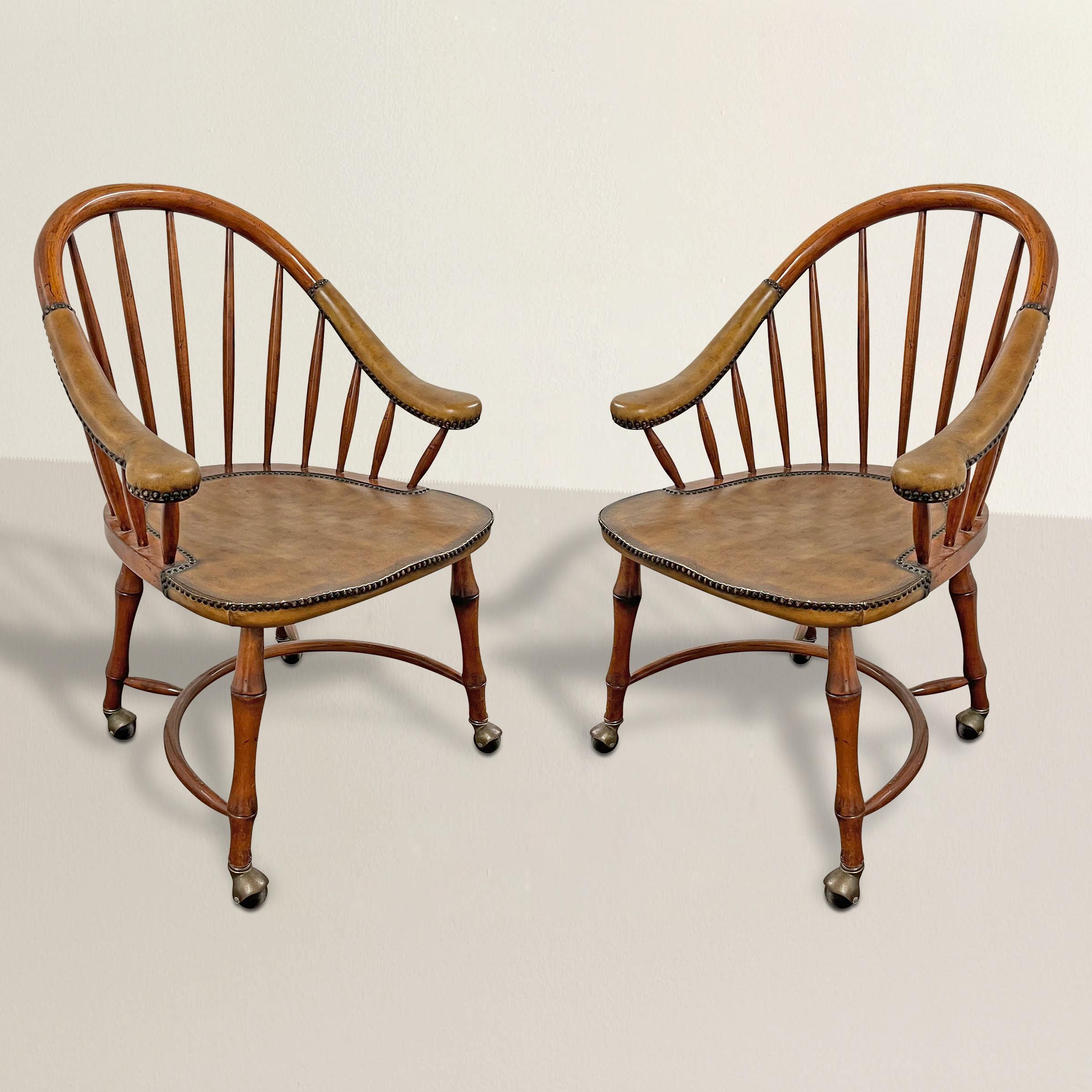 This pair of vintage 1970s American game chairs are a tasteful homage to early American Windsor design. With their hoop backs, gently sloping upholstered arms, and legs intricately carved to mimic bamboo, these chairs seamlessly merge classic