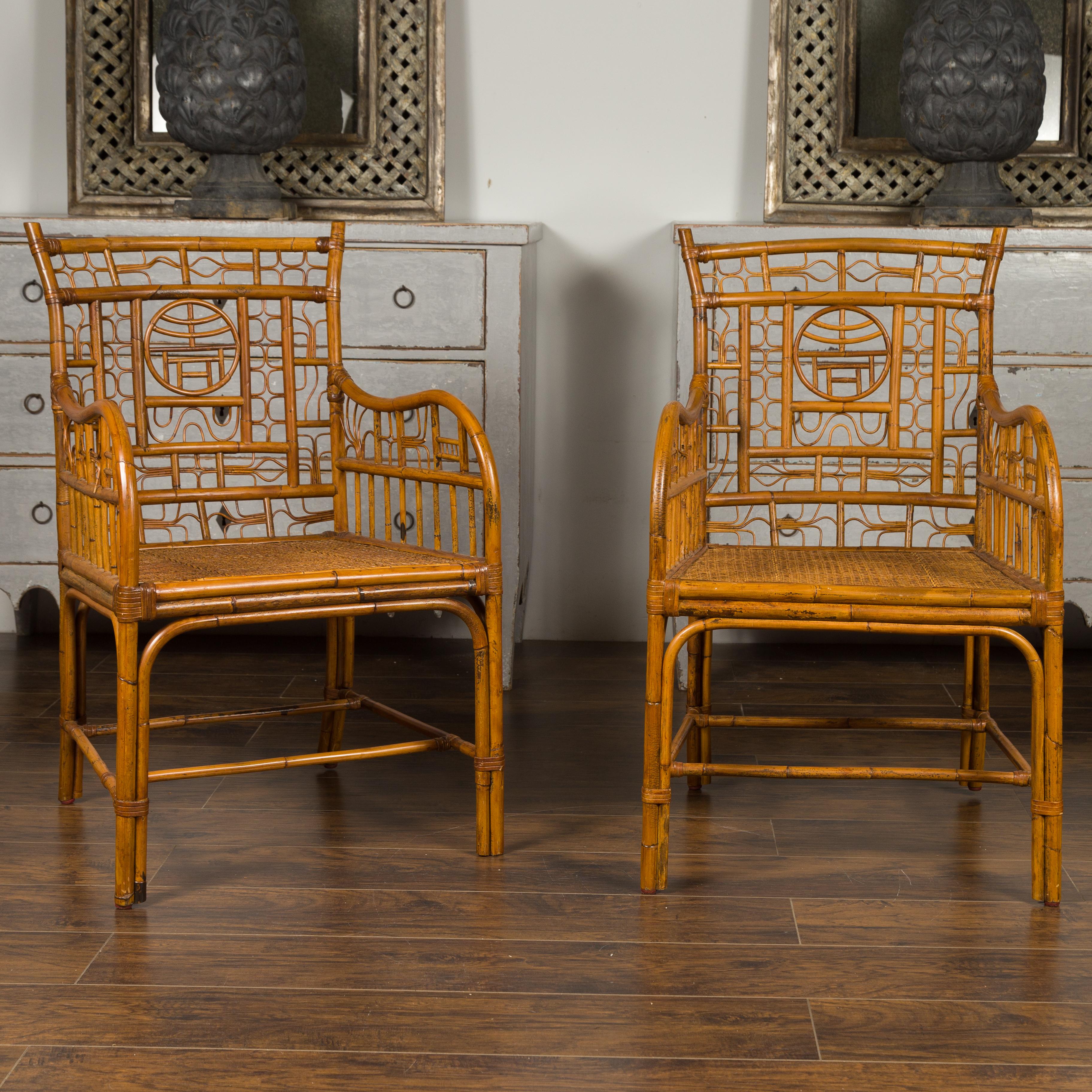 A pair of vintage American rattan armchairs from the mid-20th century, with Chinese Chippendale style motifs. Born during the mid-century period, each of this pair of rattan armchairs attracts our attention with its relaxed presence and Chinese