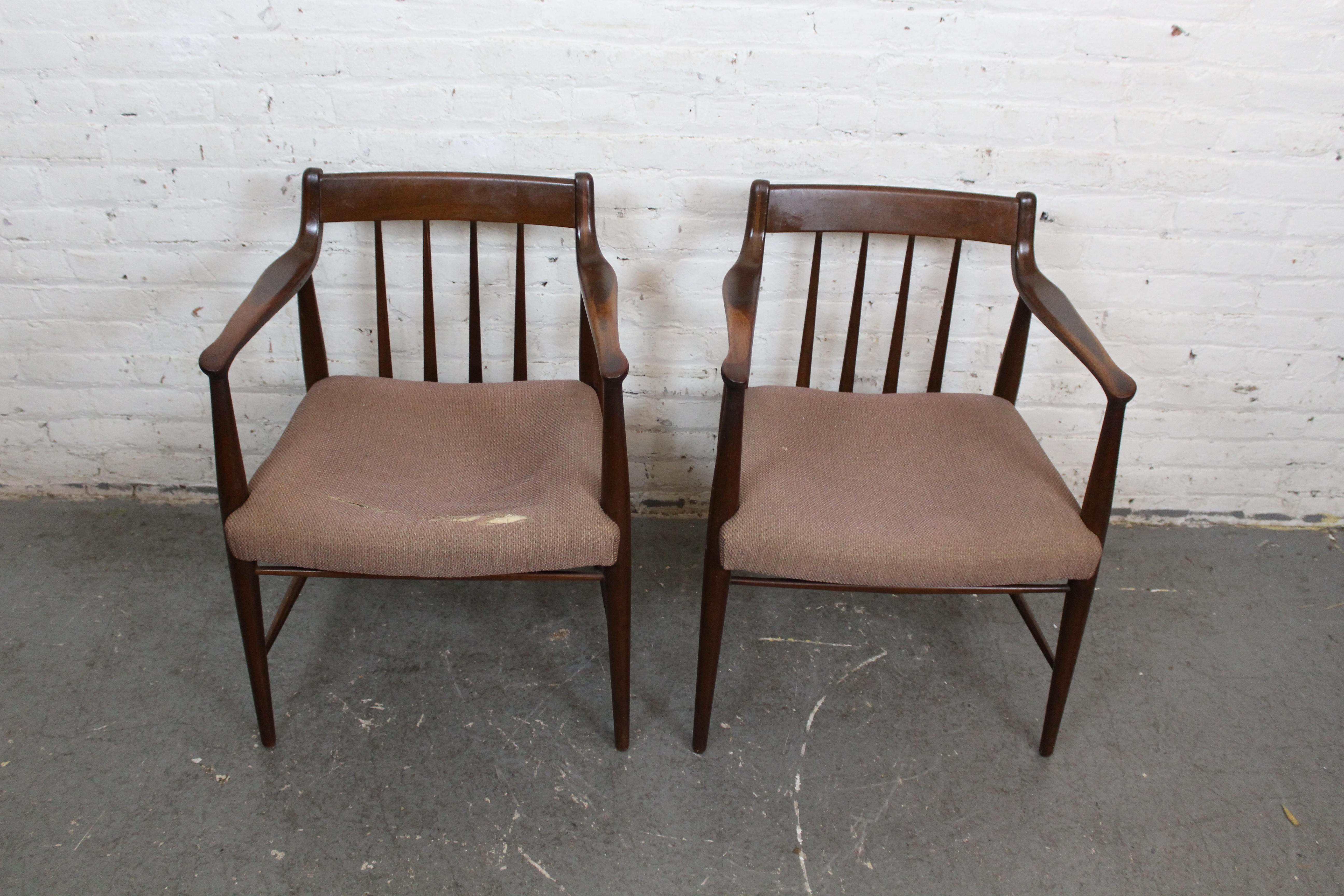 Beautiful pair of upholstered walnut vintage arm chairs produced by Heritage-Henredon of North Carolina. These quintessential mid-century chairs feature exquisitely carved solid frames, showing off ample Scandinavian modern influence reminiscent of