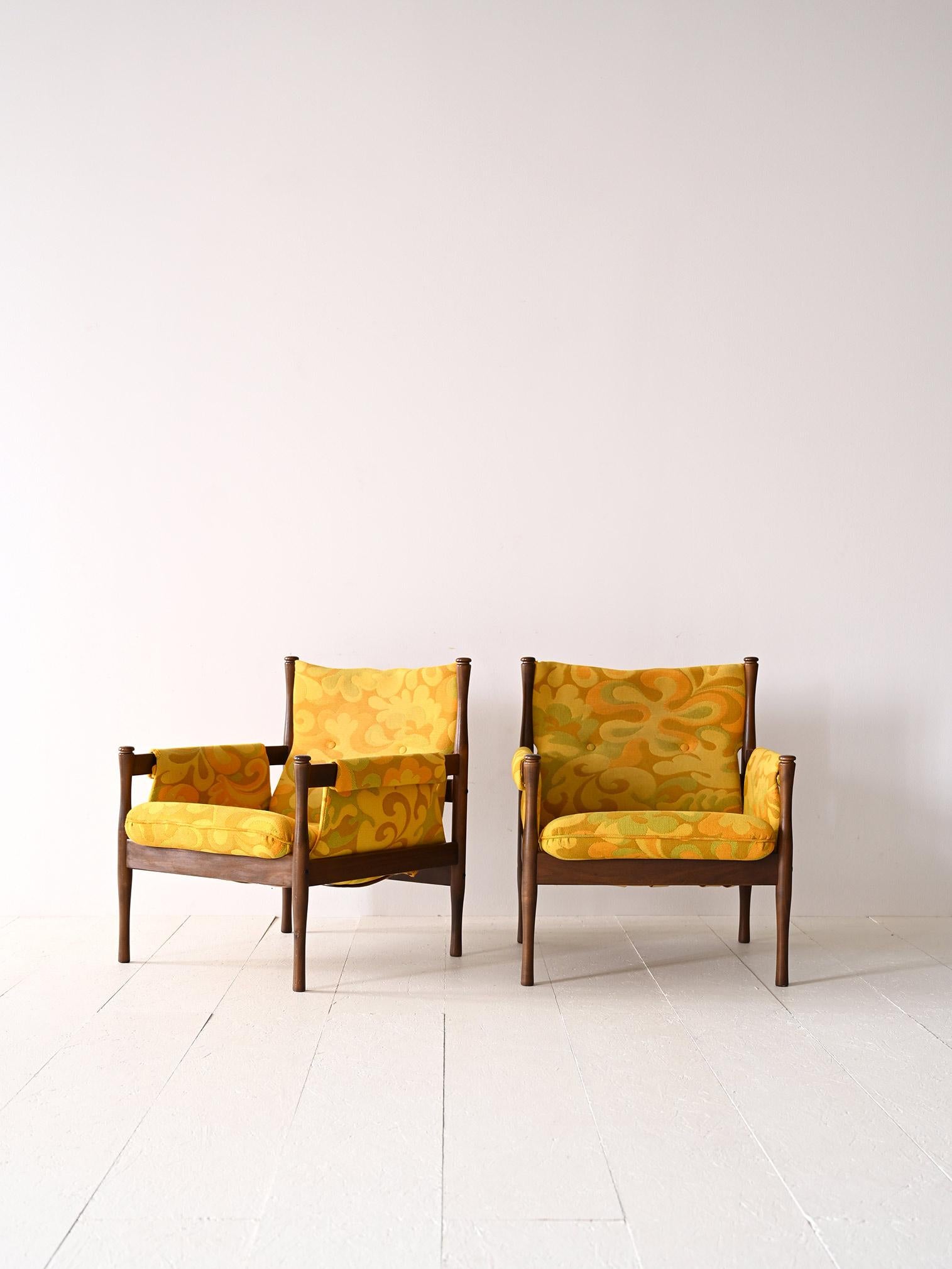 Scandinavian armchairs with wooden frames.

This pair of Swedish modernist armchairs traces mid-century taste and style.
Consisting of a square wooden frame with tapered legs and an upholstered seat and backrest reupholstered with fabric in floral