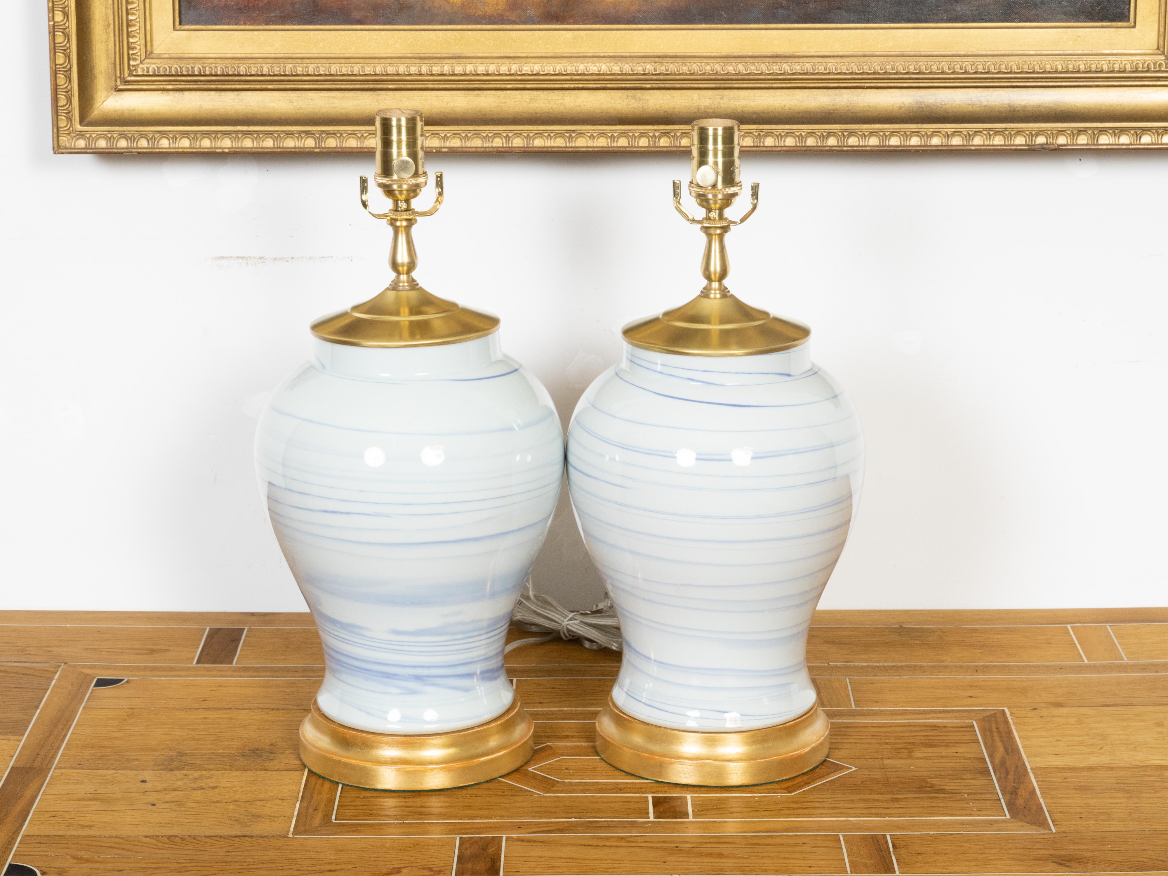 Ein Paar asiatischer weißer Porzellanvasen aus dem 21. Jahrhundert mit blauen Linien, neu montiert als Tischlampen mit einzelnen Fassungen und verkabelt für die USA. Dieses in Asien hergestellte Porzellanvasenpaar zeichnet sich durch eine