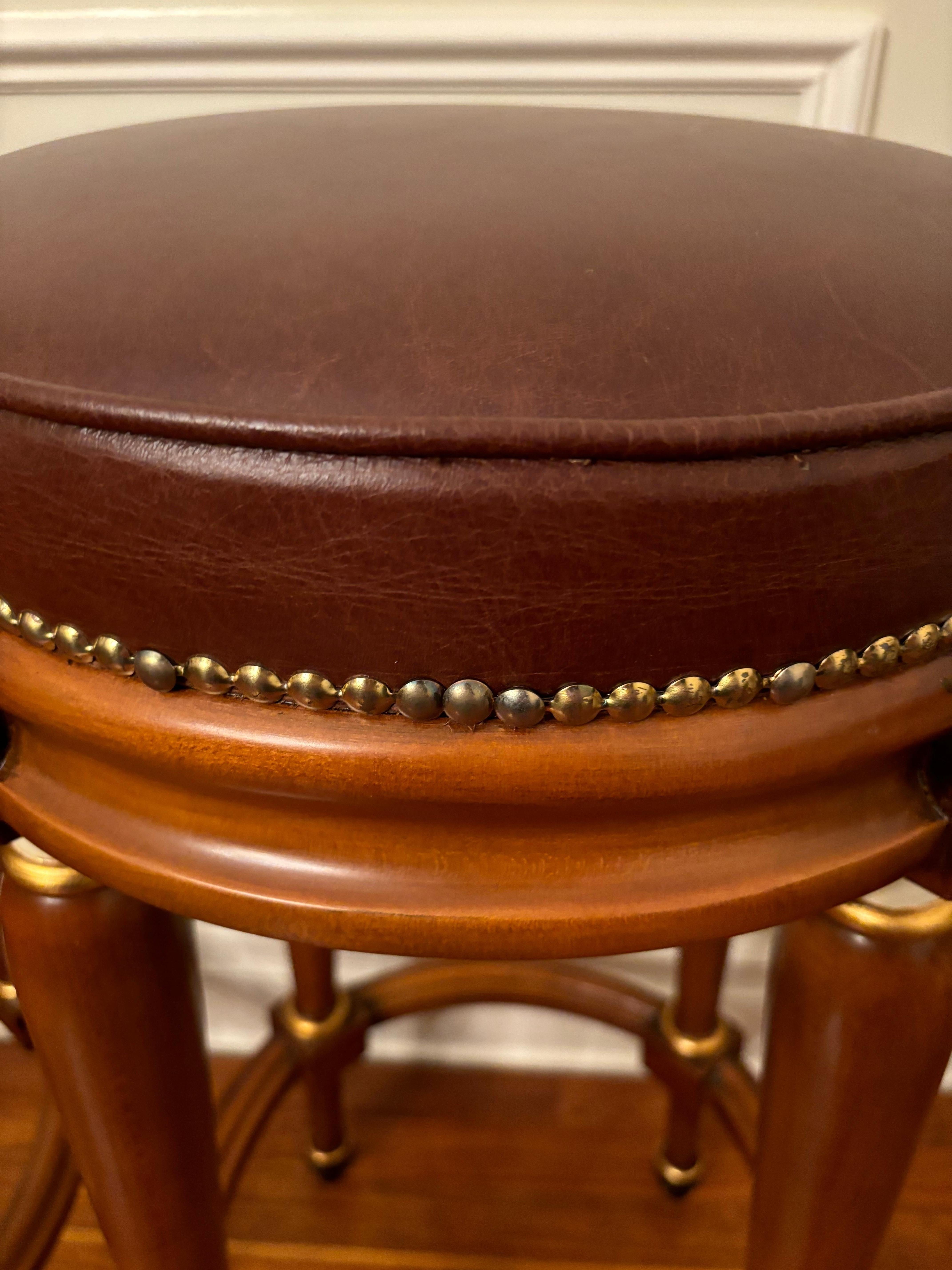 Beautiful set of 2 Vintage Asnaghi Interiors mahogany bar stools with vegan leather seats and nail heads. The minimalist design meets expert craftsmanship. Its clean, streamlined silhouette is enhanced by intricate hand carved wood accents and a