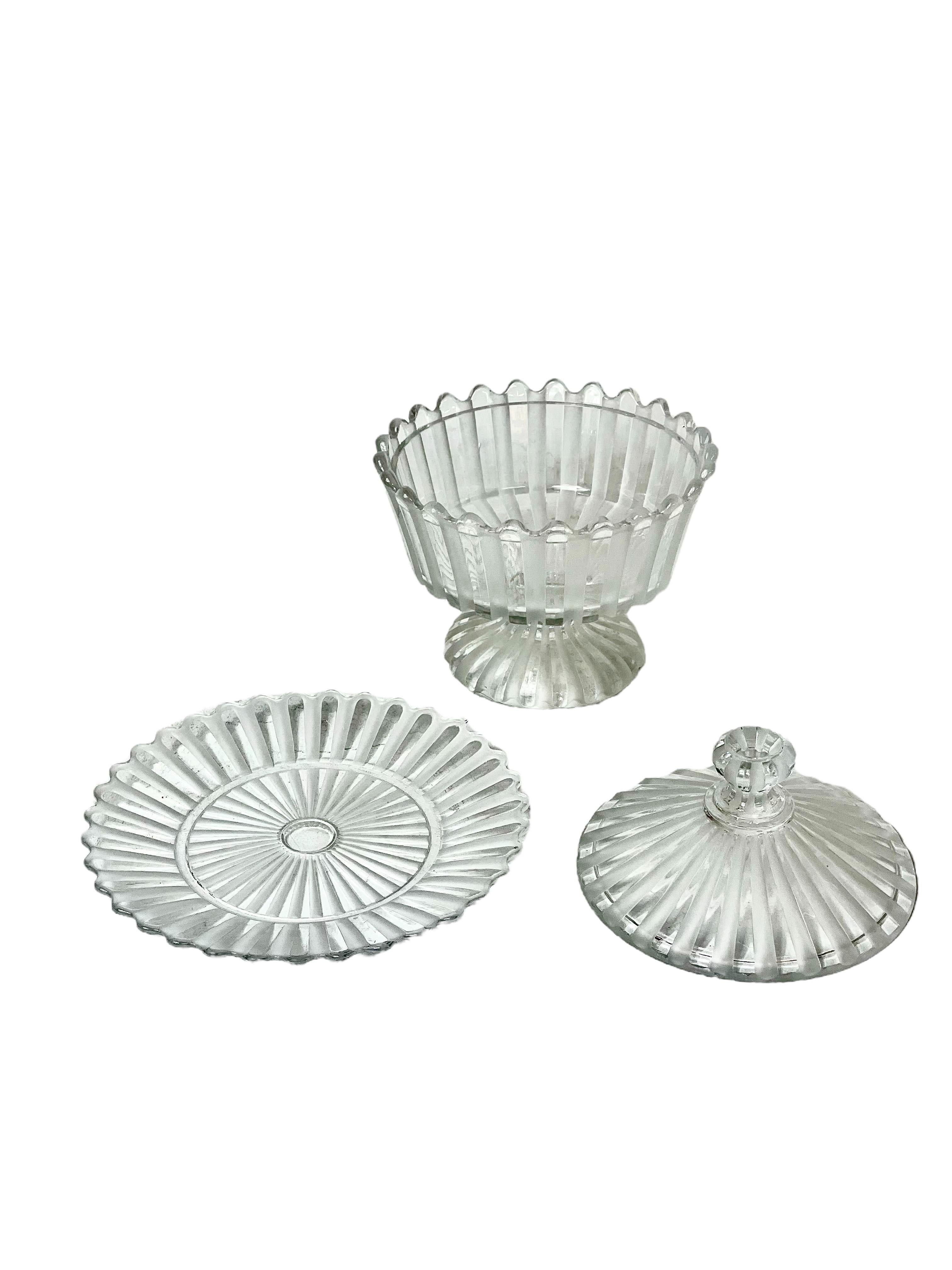 A sparkling pair of Antique Baccarat crystal 'bonbonnières', or lidded candy dishes, with matching plates. Each dish features an undulating scalloped edge, and alternating ribbed flutes of polished and frosted glass, rising on a pedestal stem from a