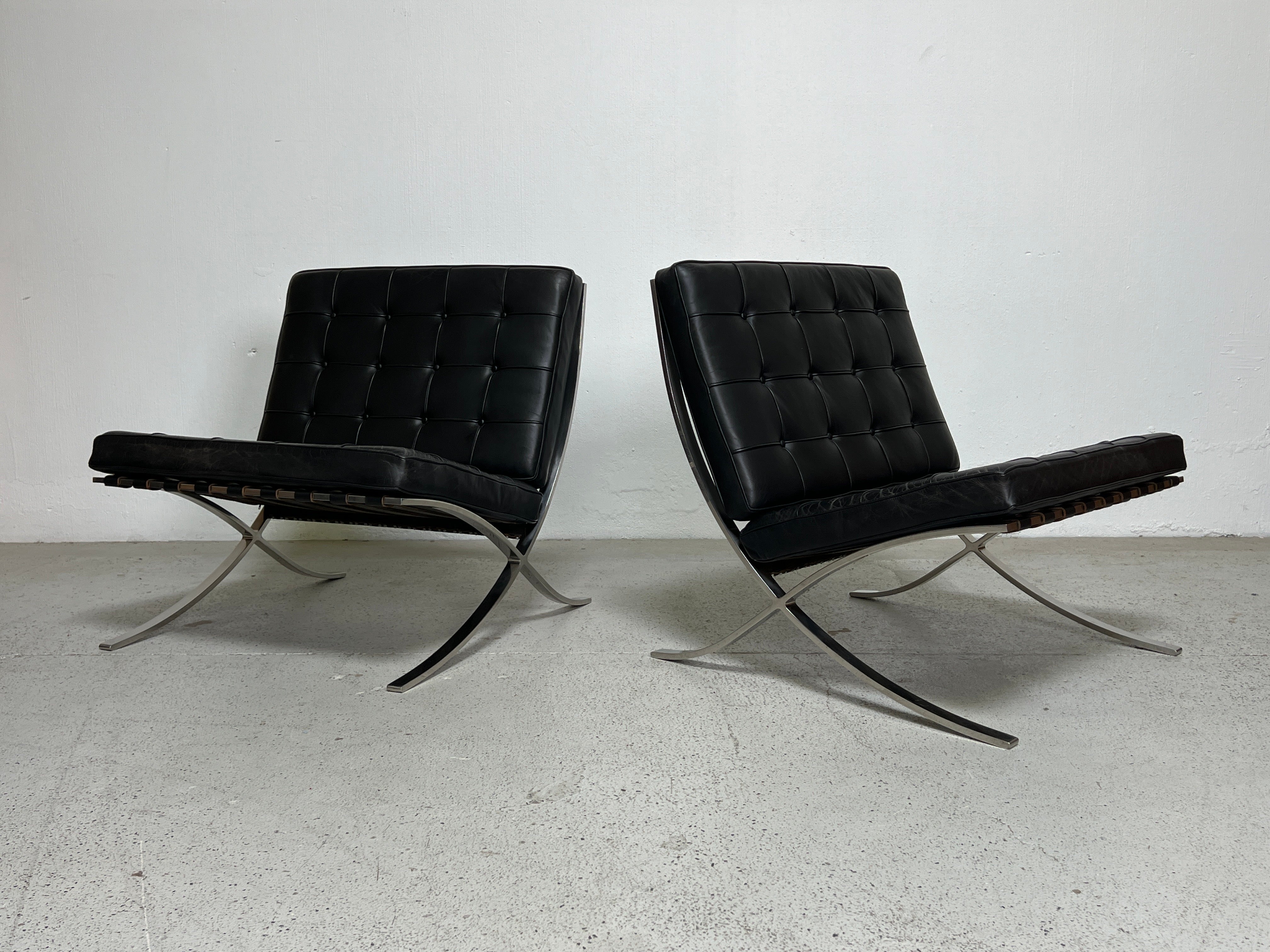 A pair of early Knoll Barcelona chairs designed by Mies van den Rohe. Stainless steel frames with patinated black leather. 