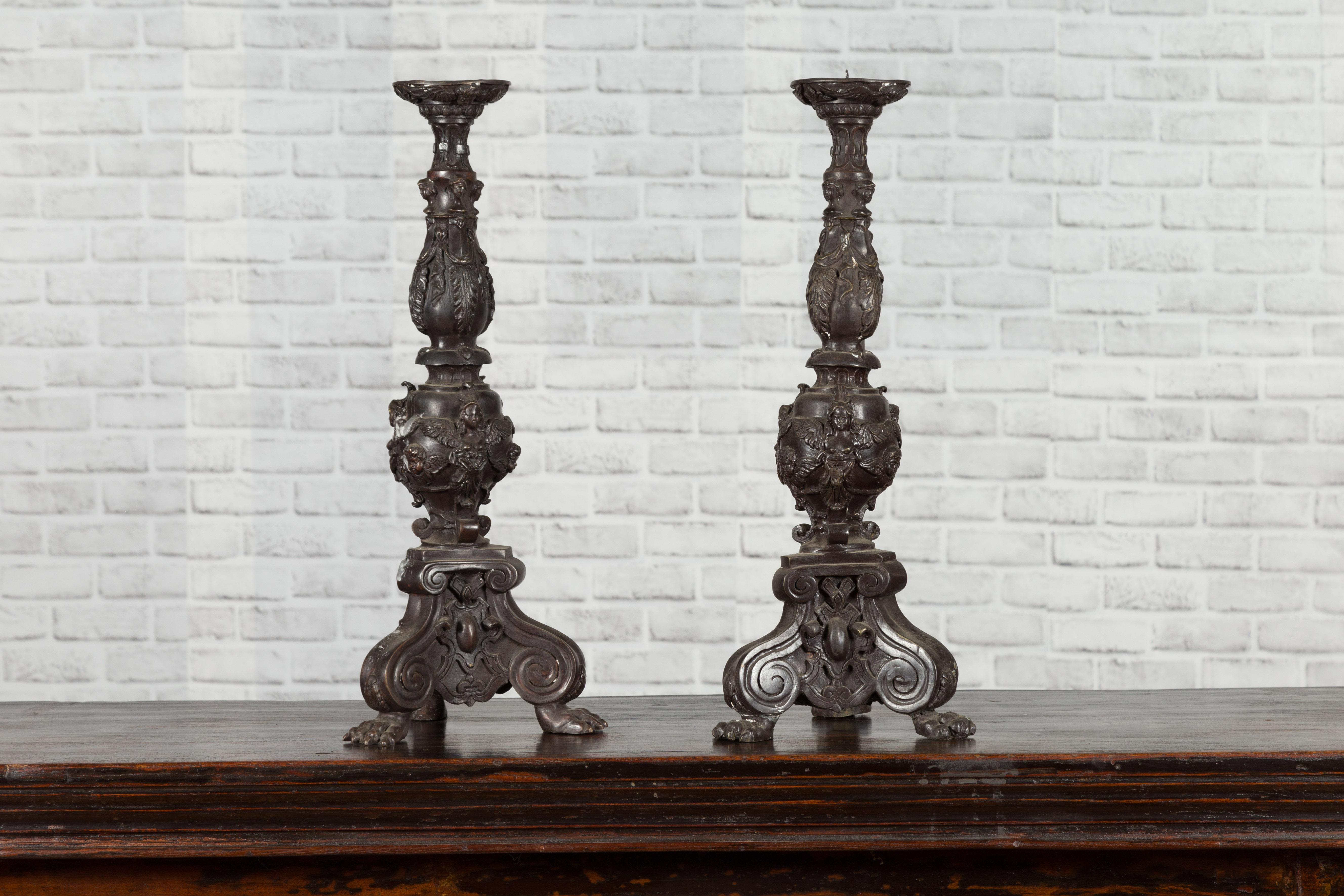 Paire de chandeliers vintage en bronze moulé de style baroque, datant du milieu du 20e siècle, avec des chérubins, des bases tripodes et des pieds en patte de lion. Créée avec la technique traditionnelle de la cire perdue qui permet une grande