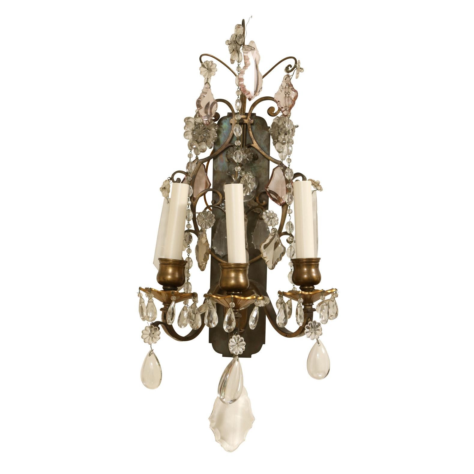 A vintage pair of French three arm sconces with beaded crystal swags, drops and attached crystal florettes. Patina to body of each sconce. Predominantly clear crystals with amber colored hanging crystals at top.
