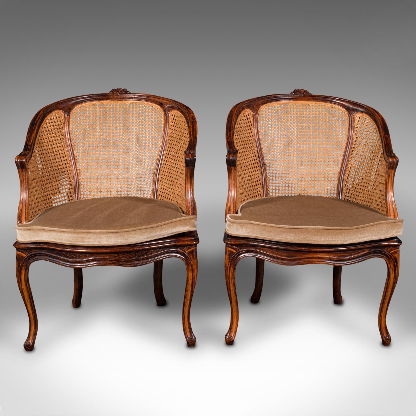 This is a pair of vintage bergère armchairs. A French, beech and cane elbow chair, dating to the mid 20th century, circa 1960.

Delightful lounge chairs with a fine appearance and finish
Displays a desirable aged patina and in good order
Beech