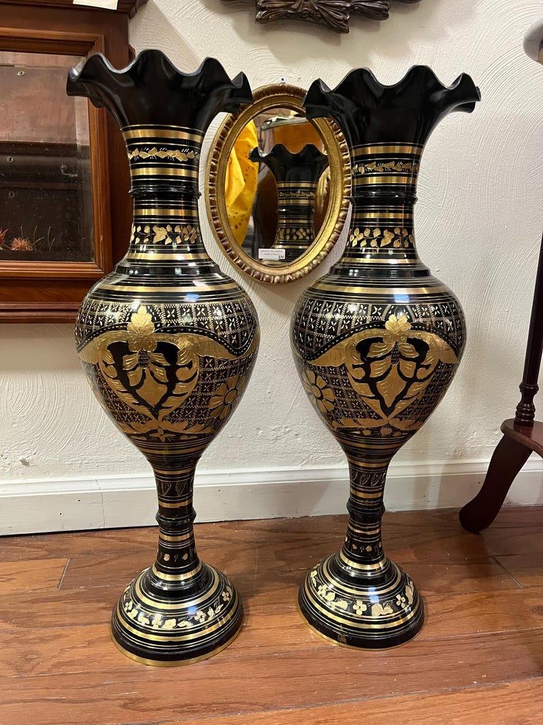This striking pair of two-foot-tall brass vases, hand-etched in India, exudes timeless elegance and exceptional craftsmanship. Each vase features a bold, bulbous shape that adds visual balance and presence, while the ruffled opening softens the