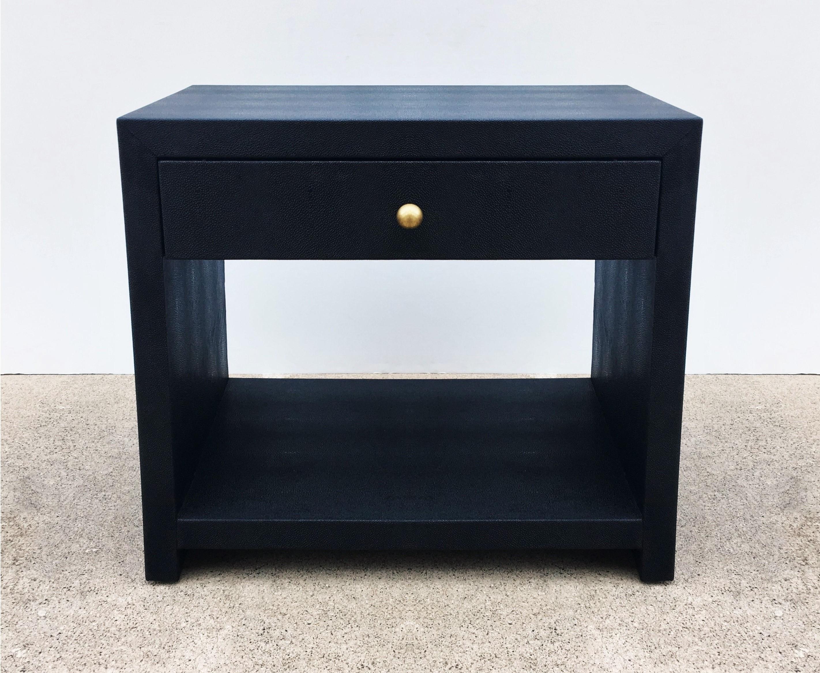 Stunning pair of 1980s nightstands in the style of Karl Springer. Made of solid wood meticulously covered in black shagreen. Clean lines open style with a single top drawer to each and a brass knob with lacquered solid oak interiors over an open