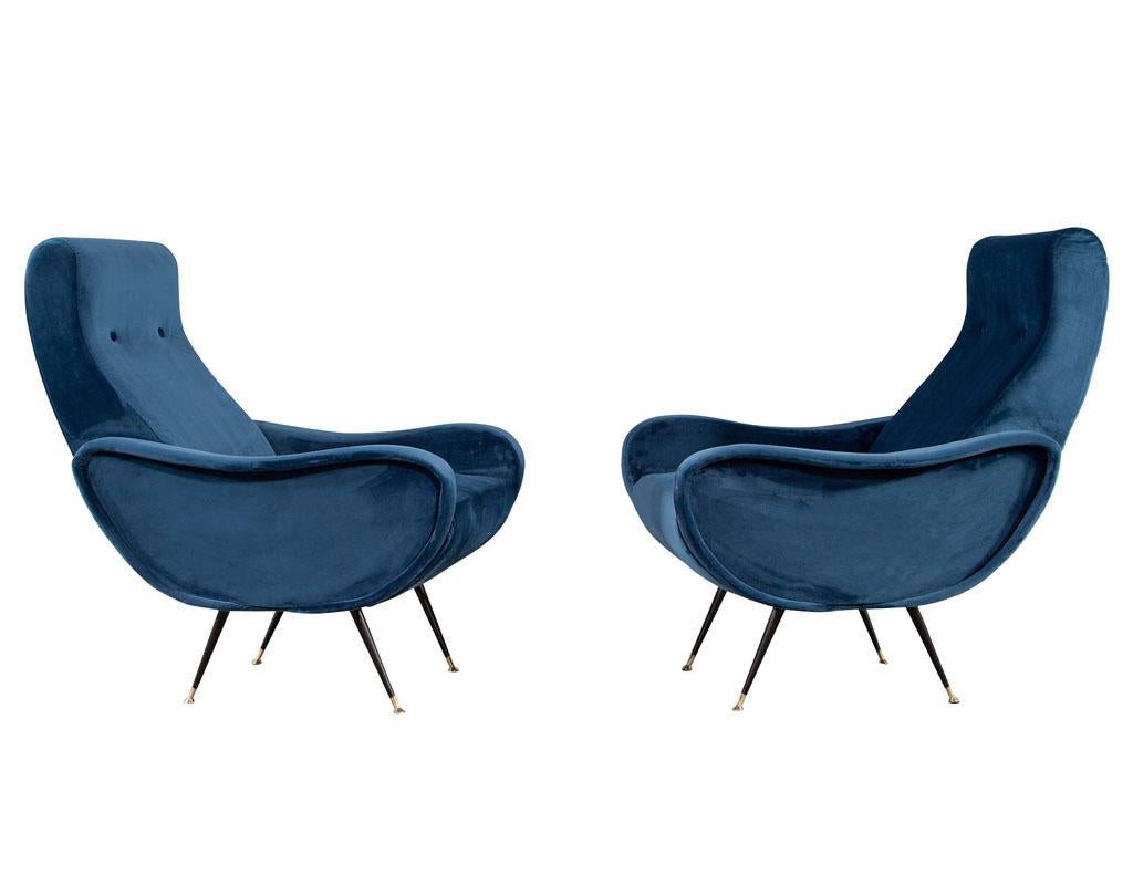 Pair of Vintage Blue Velvet Italian Lounge Chairs. Italy, circa 1980s with inspired Mid-Century Modern design. Upholstered in a blue velvet covering. All original in good condition. Resting upon 4 sleek stain black metal legs with metal foot caps.