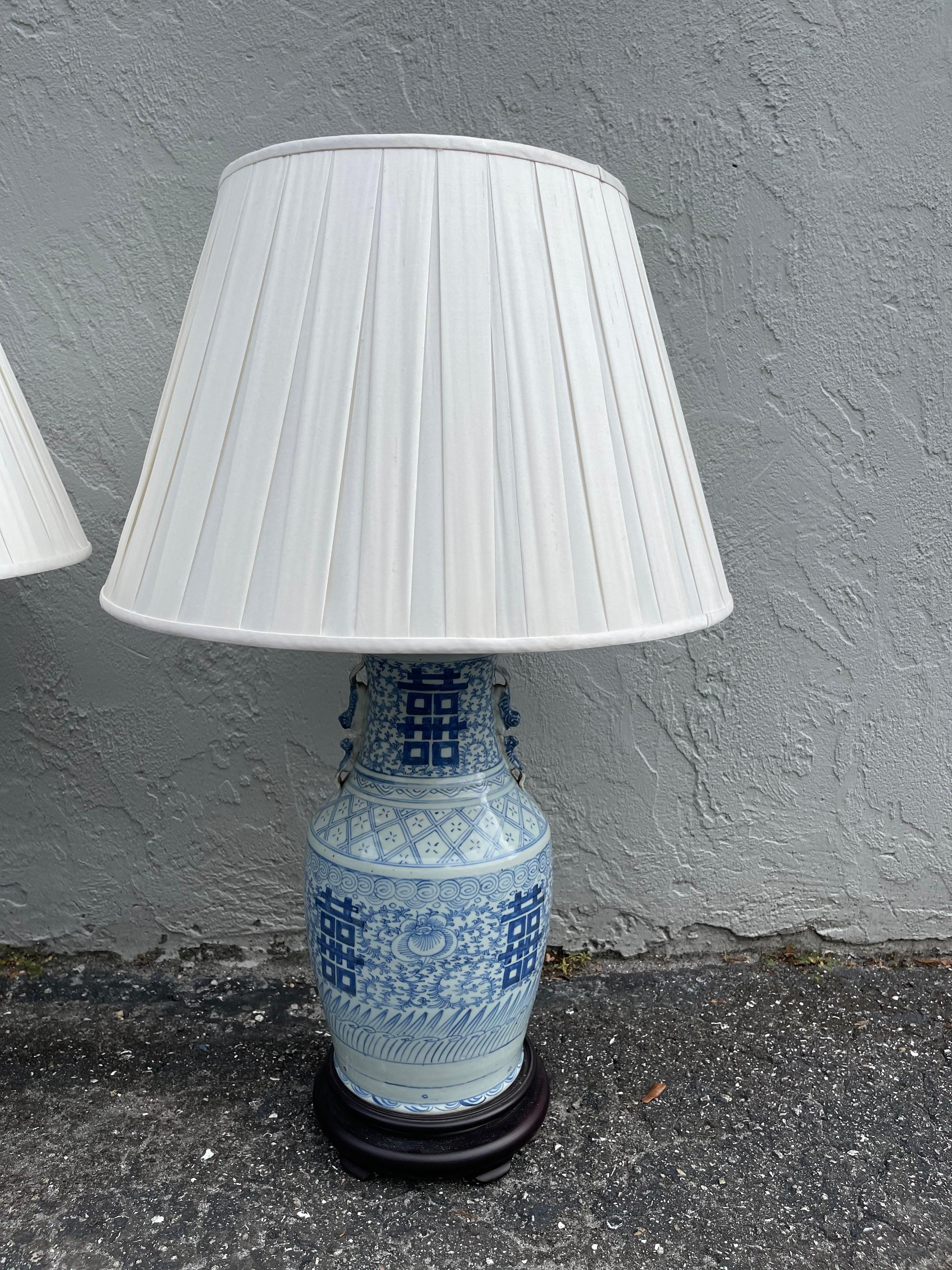 Vintage pair of large blue & white Chinese lamps with white shades. These beautiful lamps were made from 19th century vases. Newer shades.