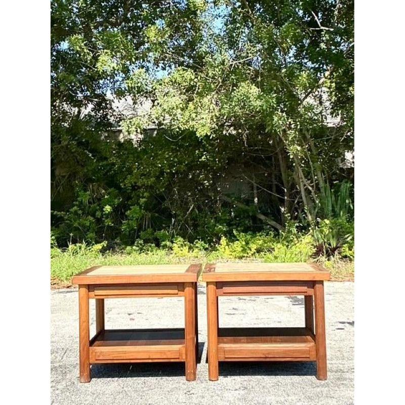 Introduce a blend of sophisticated natural materials and vintage charm with this lovely pair of teak side tables featuring inset travertine tops. Each table is crafted from warm-toned teak wood, forming a clean-lined frame that beautifully