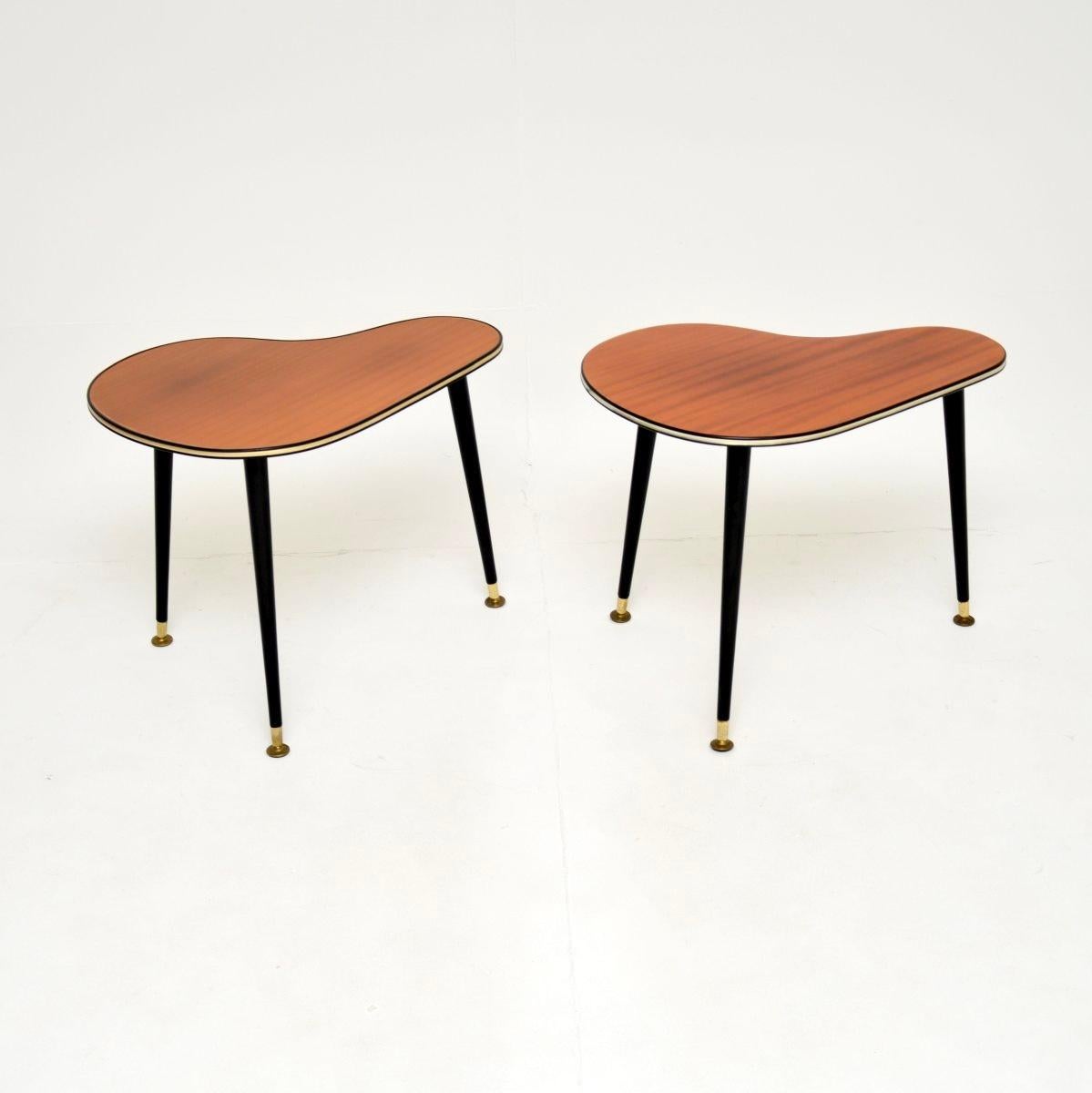 A stylish pair of vintage boomerang side tables. They were made in England, they date from the 1950’s.

The tops are lacquered wood, they stand on black tapered legs with brass feet caps and brass banding around the top edges.

They are beautifully