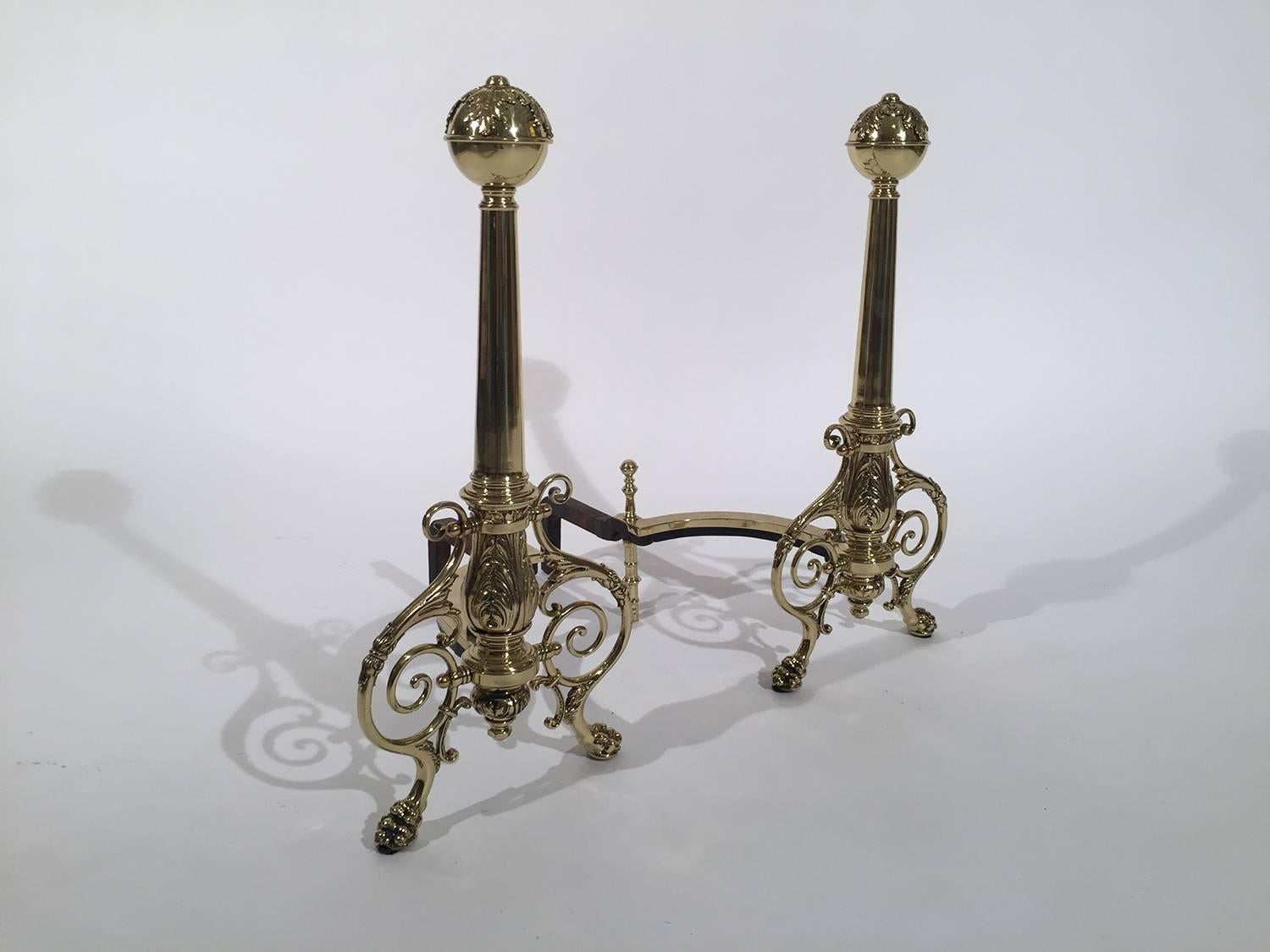 A graceful pair of polished cast brass Louis XV style andirons. The sphere tops with tapered columns supported by scrolled legs with acanthus leaf decoration.
  