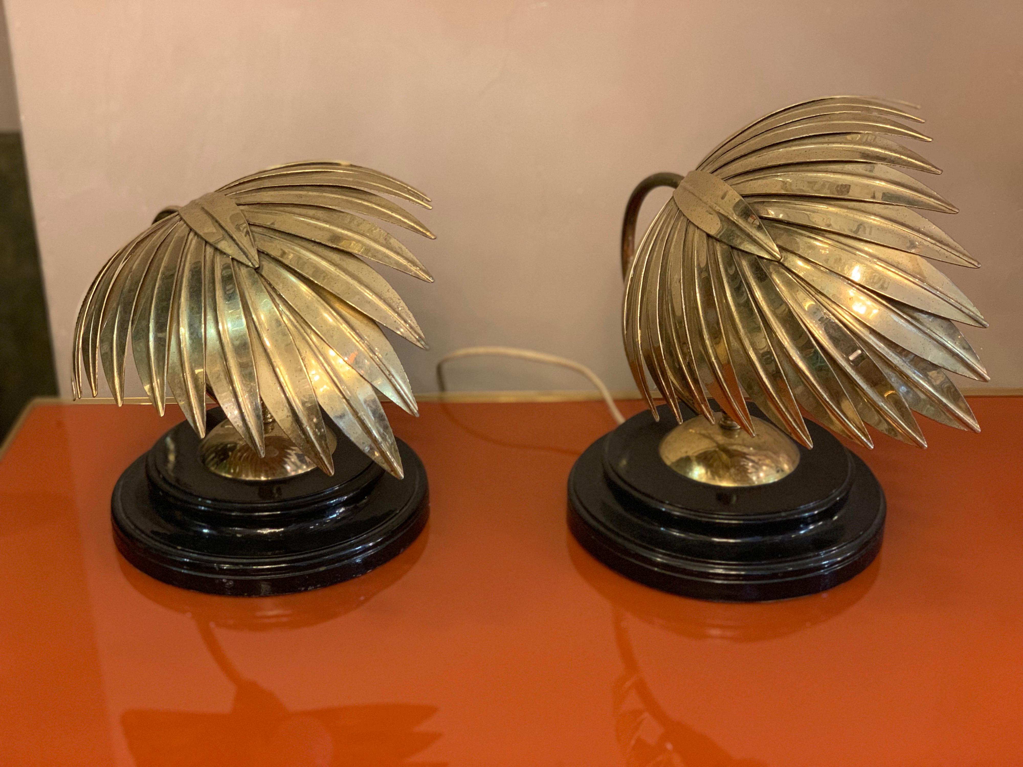 Pair of vintage brass leaf bedside lamps with round black lacquered base.
One bulb per lamp. 
Good vintage condition with small imperfections consistent with age which increase its flavor.