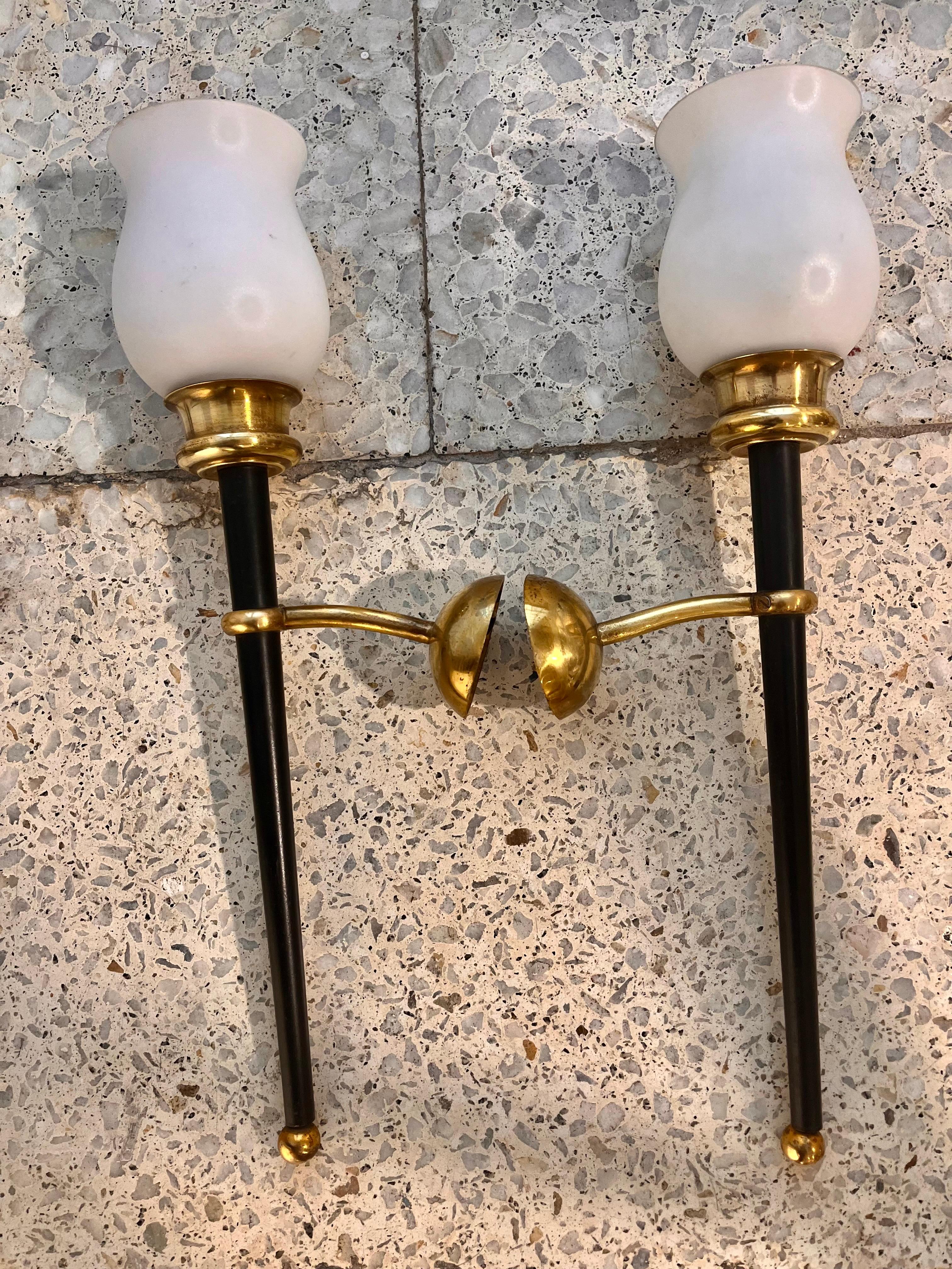 Pair of vintage wall lights, in the style of Maison Arlus, torch-shaped, with a central column of black lacquered metal, ending in a ball at the bottom, a gilded brass support, and the lampshades are the original ones, in white opaline.