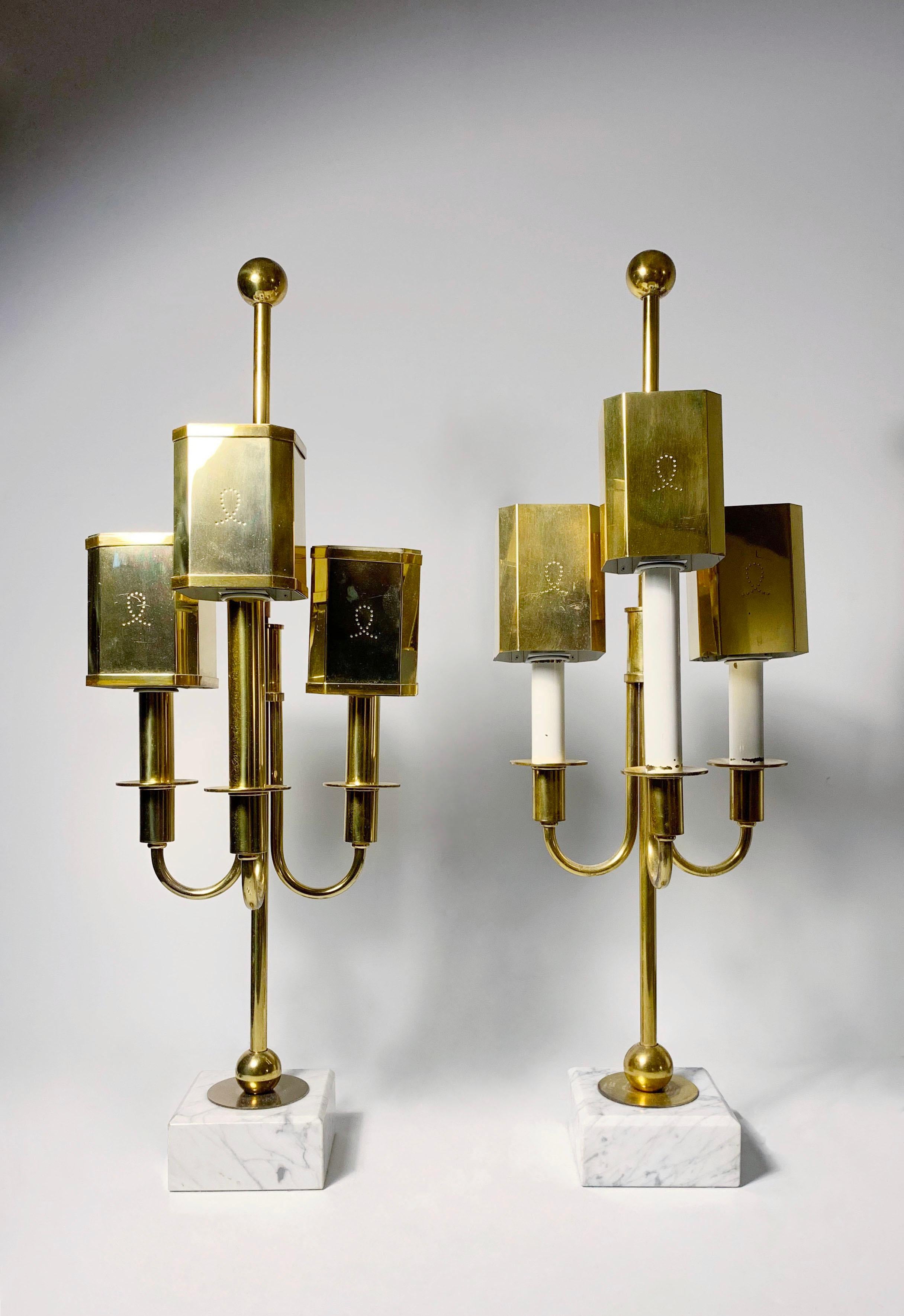 Pair of vintage brass table lamps in the manner of Tommi Parzinger. Possibly Swedish. No identifying marks.

Some very subtle differences between the pair. 
White painted candle version is ever so slightly taller. does not have the brass borders on