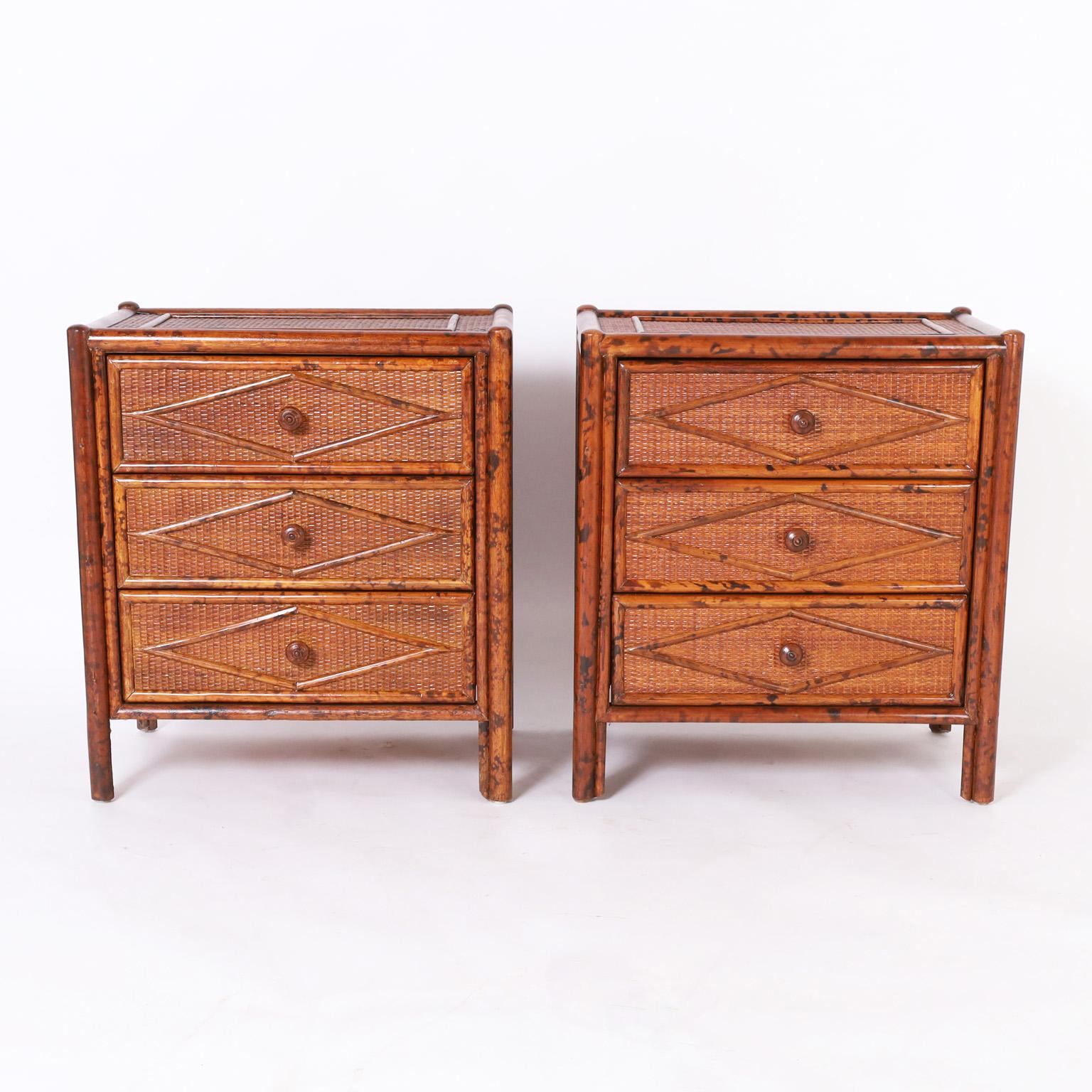 Midcentury British Colonial style three drawer stands crafted with faux bamboo frames having a faux tortoise finish and grasscloth panels all around with applied geometric design.